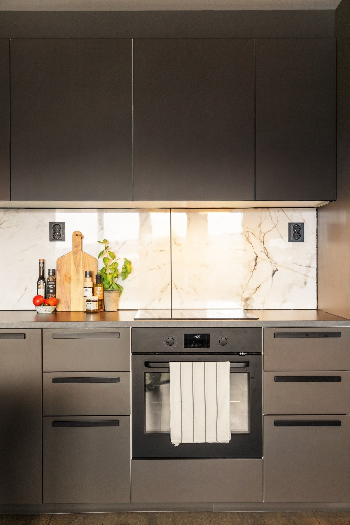 Benkeplaten er utført i en slitesterk laminatkvalitet med god arbeidsflate, og over benk er det montert storformat veggplater med marmorert uttrykk som tilfører rommet et sofistikert og tidløst særpreg. Galleribilde