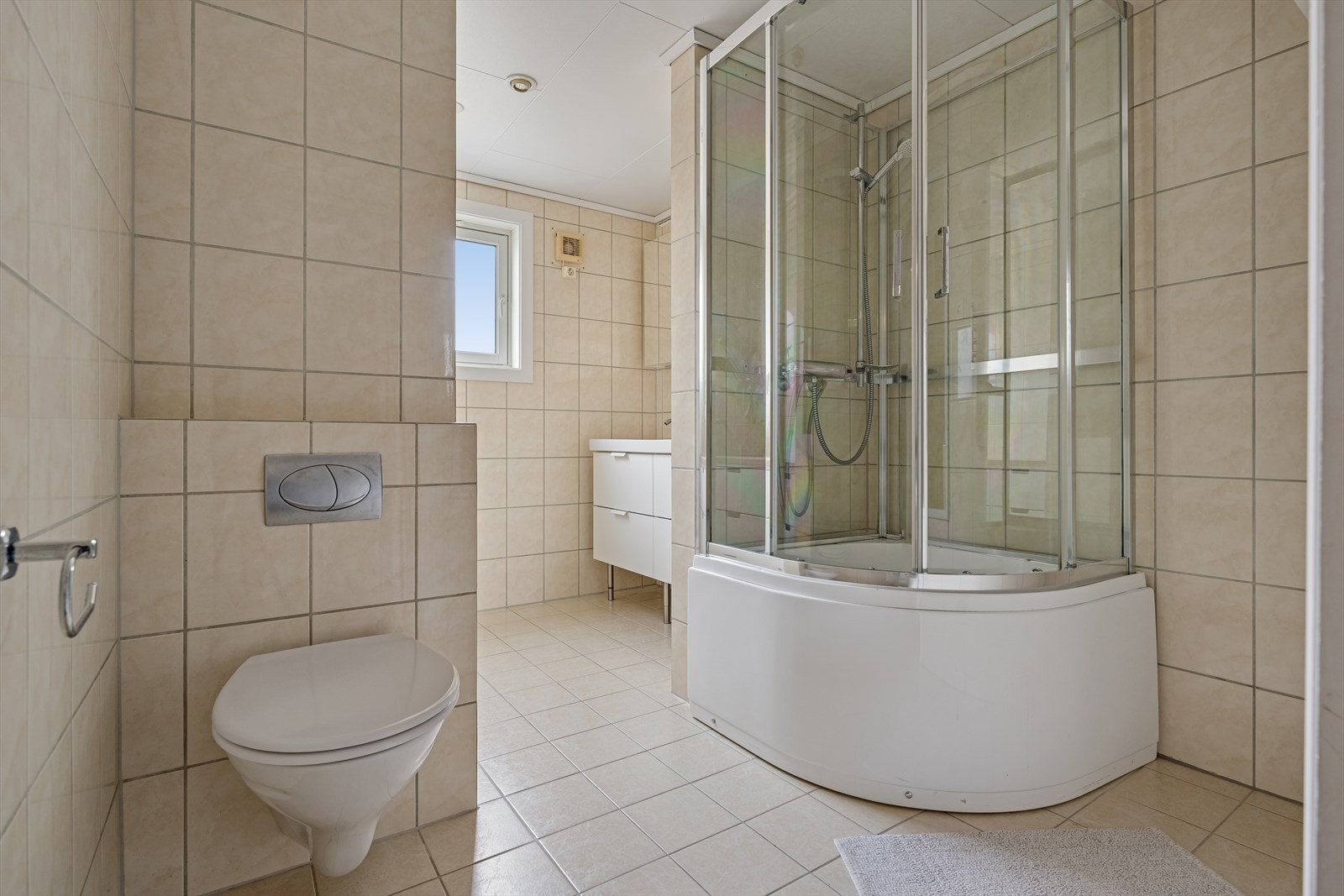 Baderommet er fra tidlig 2000-tallet og er innredet med beige, sjatterte fliser på gulv og vegger. I gulvet har man også varmekabler for ekstra komfort. Galleribilde