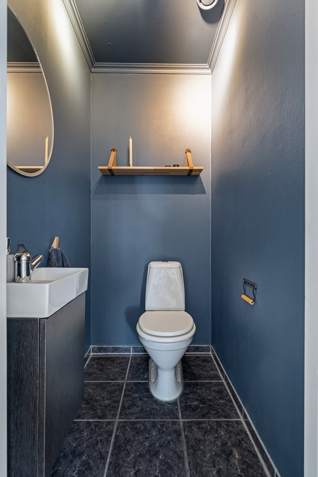 Praktisk gjestetoalett innredet med flislagt gulv og malte flater. Rommet er ellers utstyrt med toalett og baderomsinnredning med nedfelt servant. Galleribilde