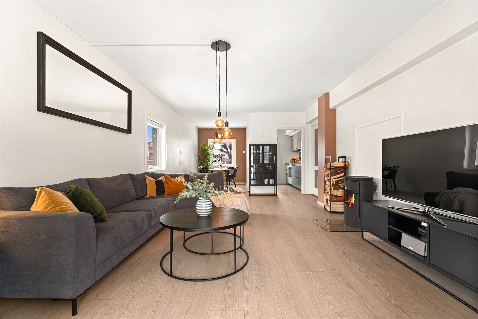 Åpen stue/spisestue med gjennomgående flott gulv, lyse vegger, gjennomgående dagslys i tillegg til ekstra vindu siden denne leiligheten ligger på en ende Galleribilde