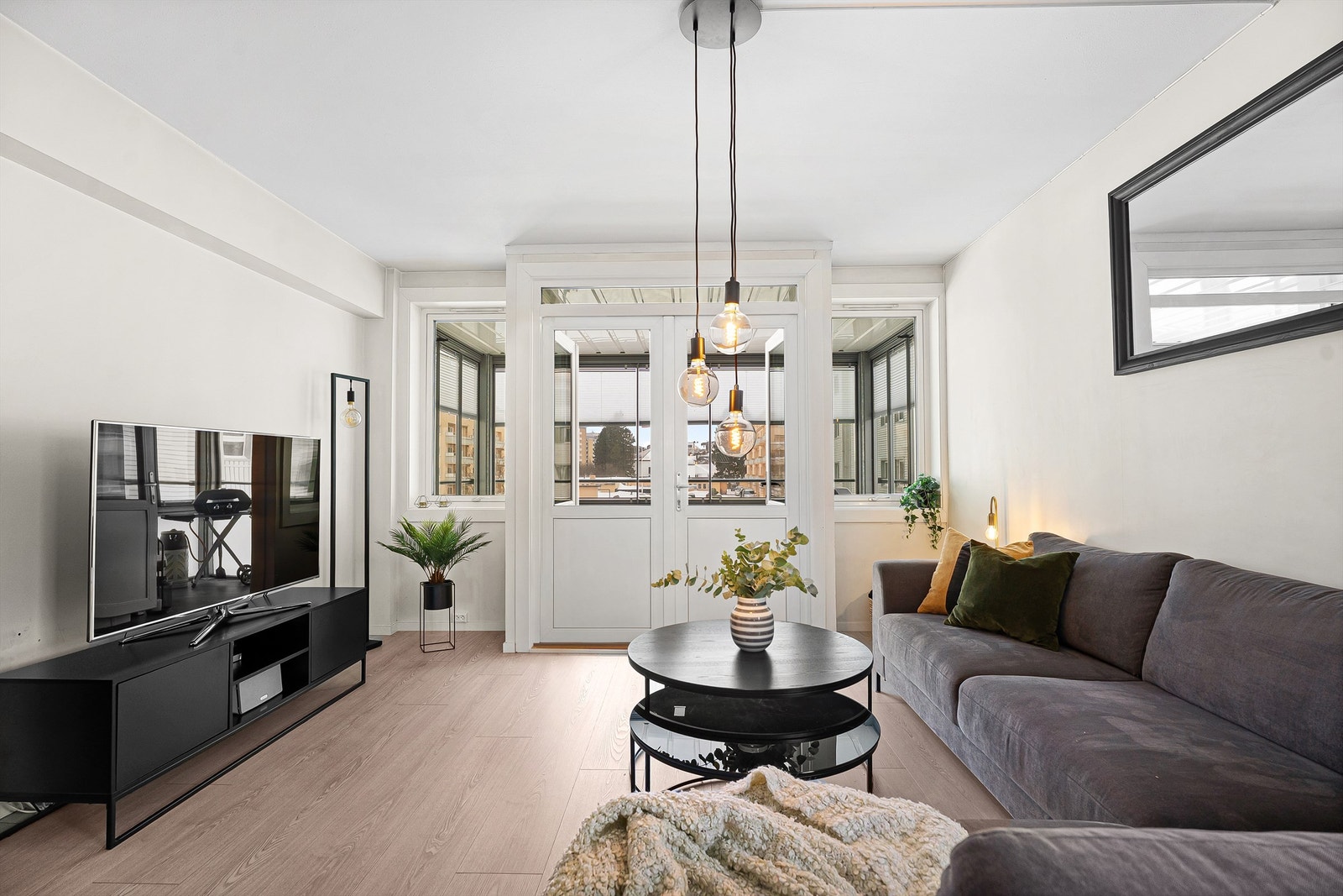 Stuens dør til innglasset balkong gir mye dagslys inn i leiligheten Galleribilde