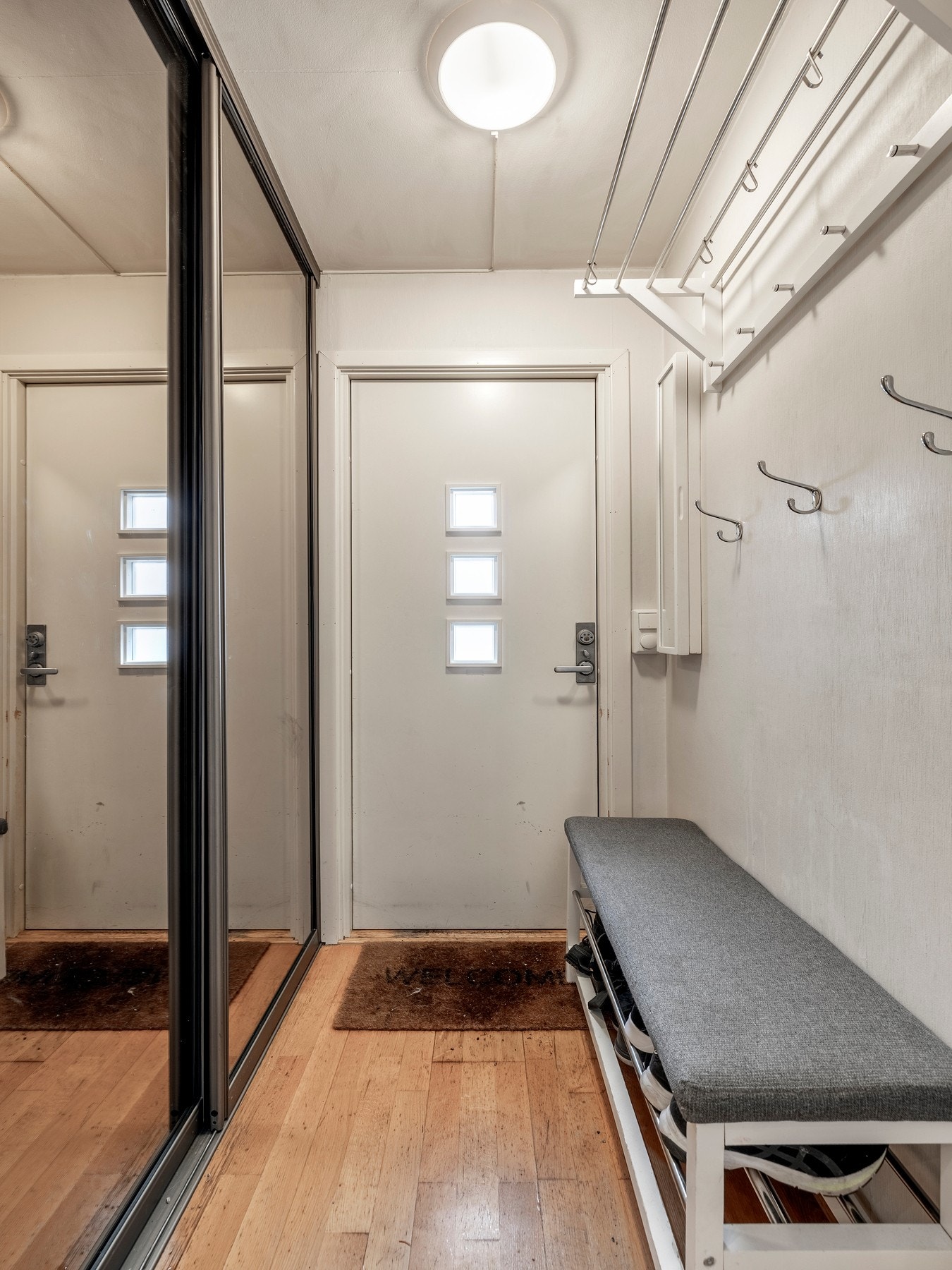 Entréen har plass til sittebenk, og rommet er innredet med en praktisk skyvedørsgarderobe med speilfronter. Galleribilde