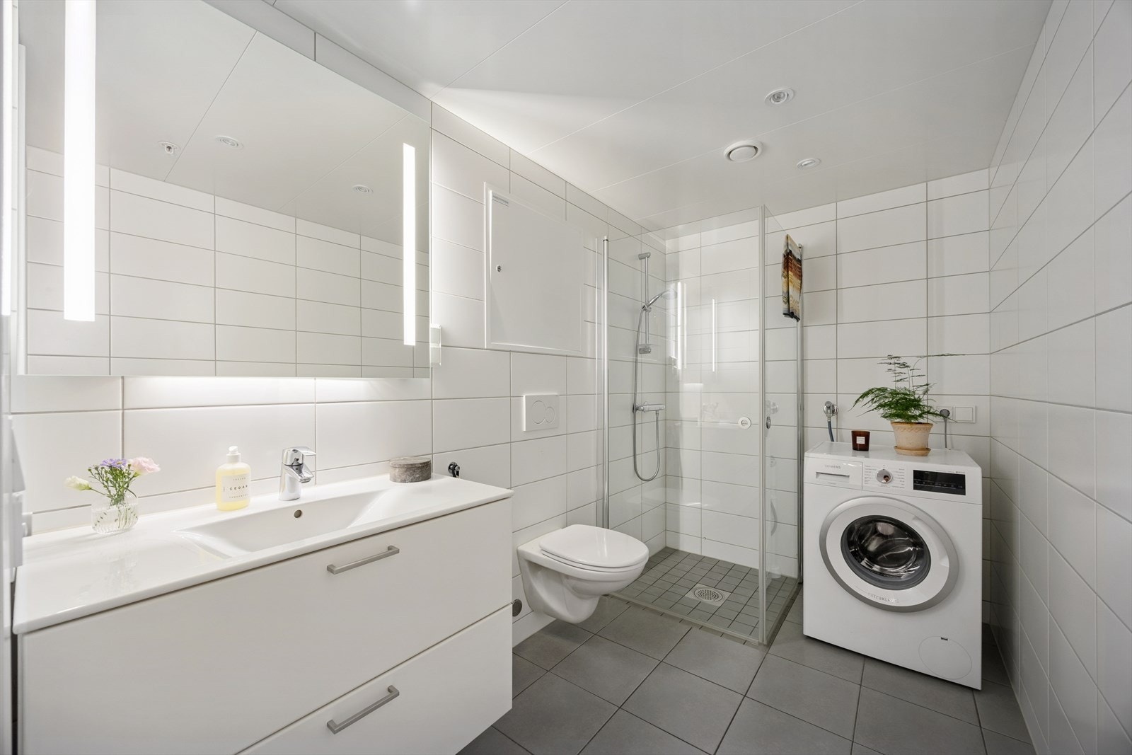 Flislagt baderom med opplegg for vaskemaskin, varme i gulvet og downlights i himlingen. Galleribilde