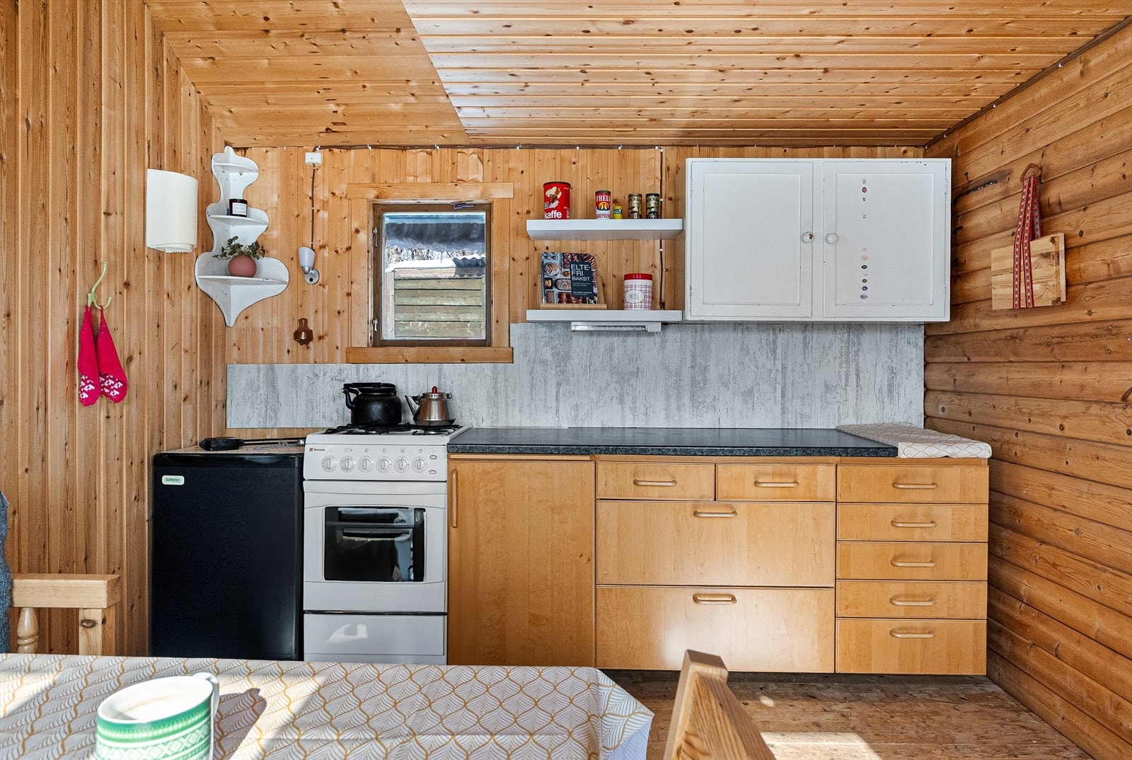 Her har du innredning med laminerte skorg og slette fornter, laminert benkeplate, frittstående gassdrevet komfyr med gassbluss og kjøleskap. Det er også montert gassalarm. Galleribilde