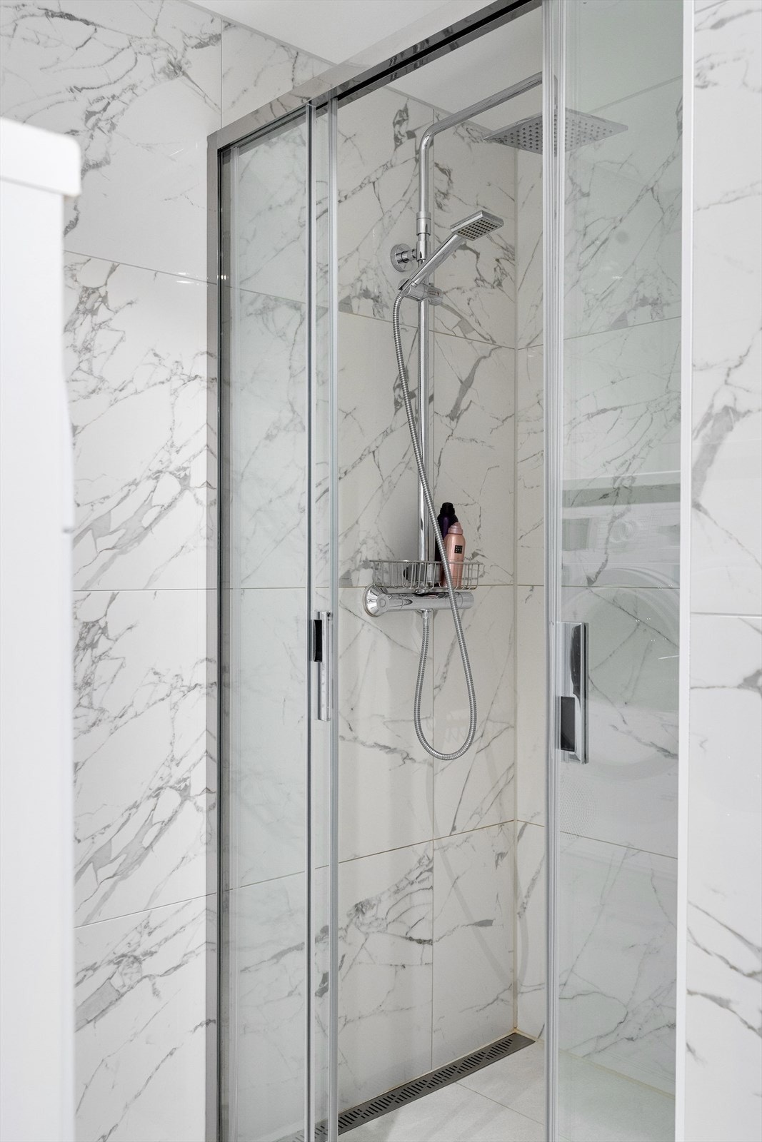 Moderne innredet med vegghengt toalett, romslig dusjnisje, håndkletørker, moderne innredning og plass til vaskemaskin og tørketrommel. Galleribilde