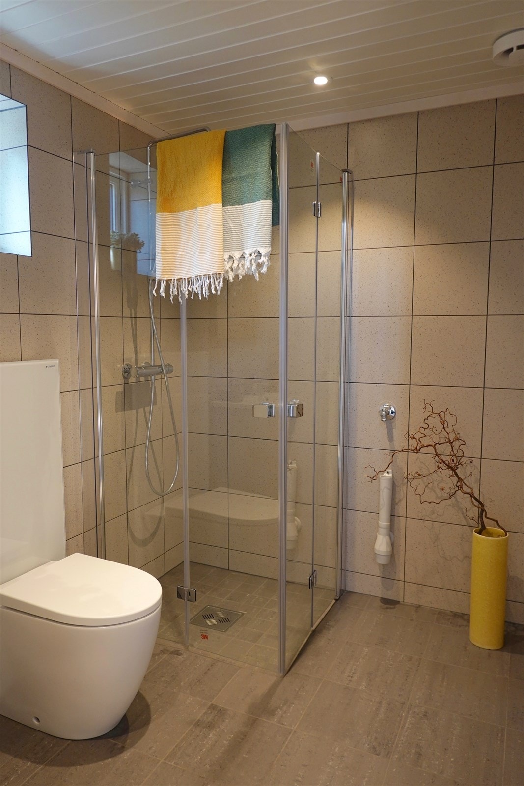 Badet er innredet med fliser på gulv og baderomsplater på vegger. Galleribilde