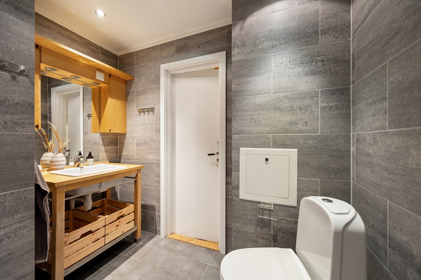 Rommet er innredet med toalett, en servant nedfelt i baderomsinnredningen og et dusjhjørne med svingbare glassdører samt opplegg for vaskemaskin. Galleribilde