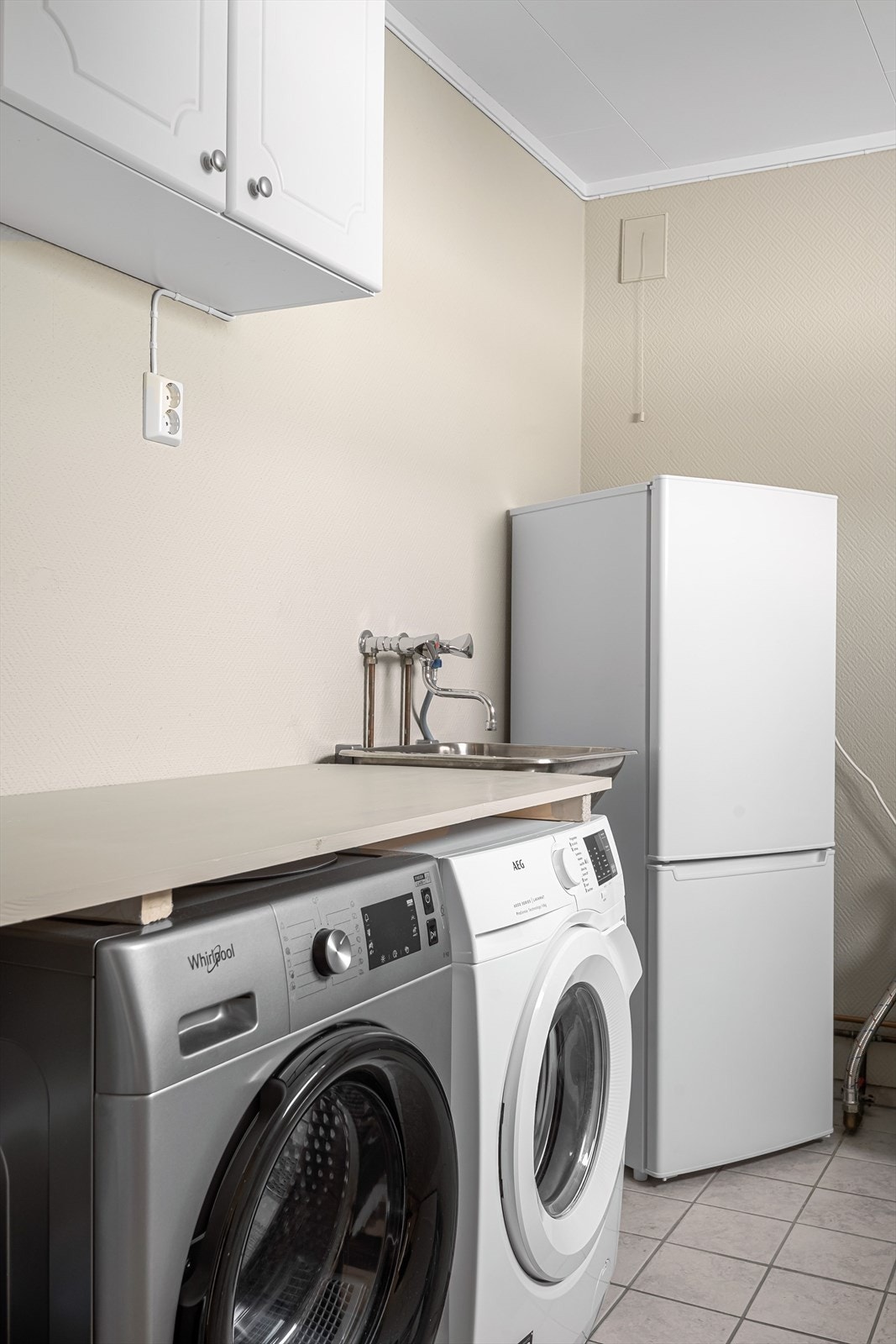 Benk og skap som forenkler klesvasken. Her er det flisalgt gulv med varmekabler og malte vegger. Galleribilde