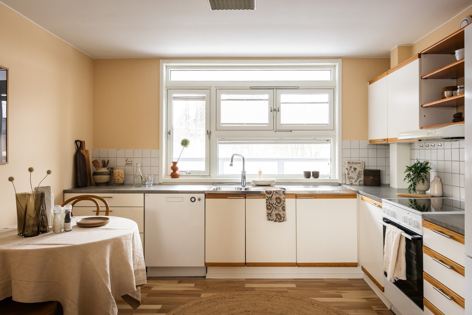 Velholdt og pen kjøkkeninnredning med hvite fronter. Fliser over benkeplaten. Galleribilde