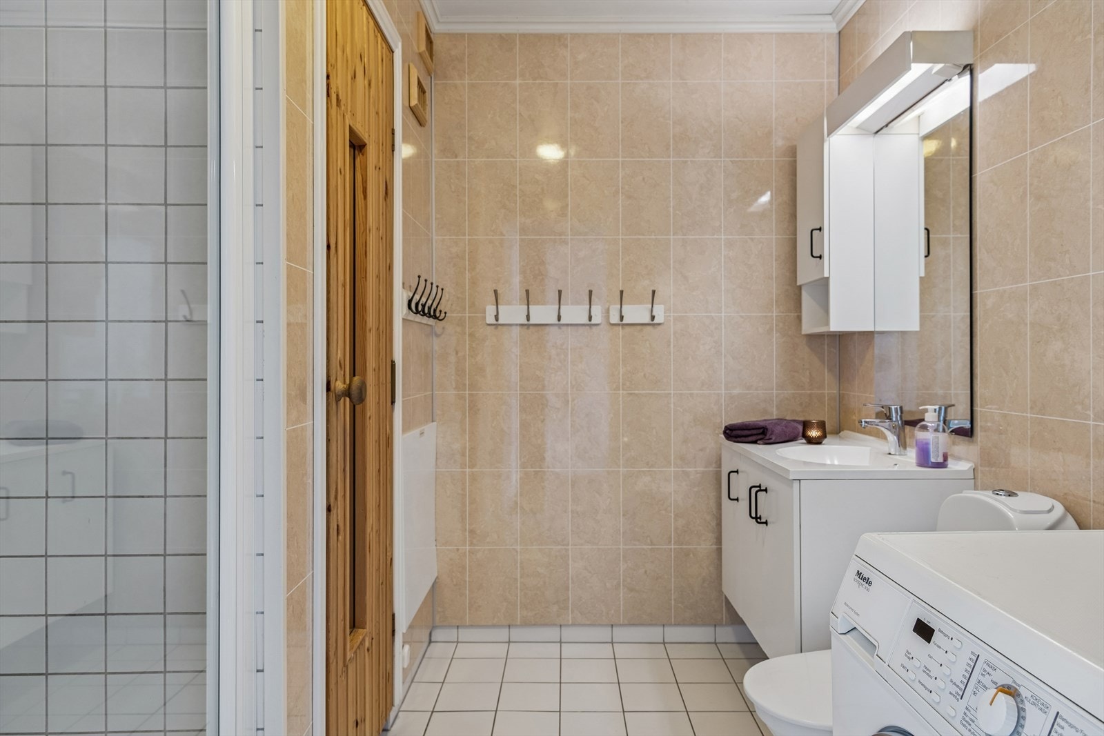 Badet har flislagt gulv med elektrisk gulvvarme og opplegg for vaskemaskin. Galleribilde