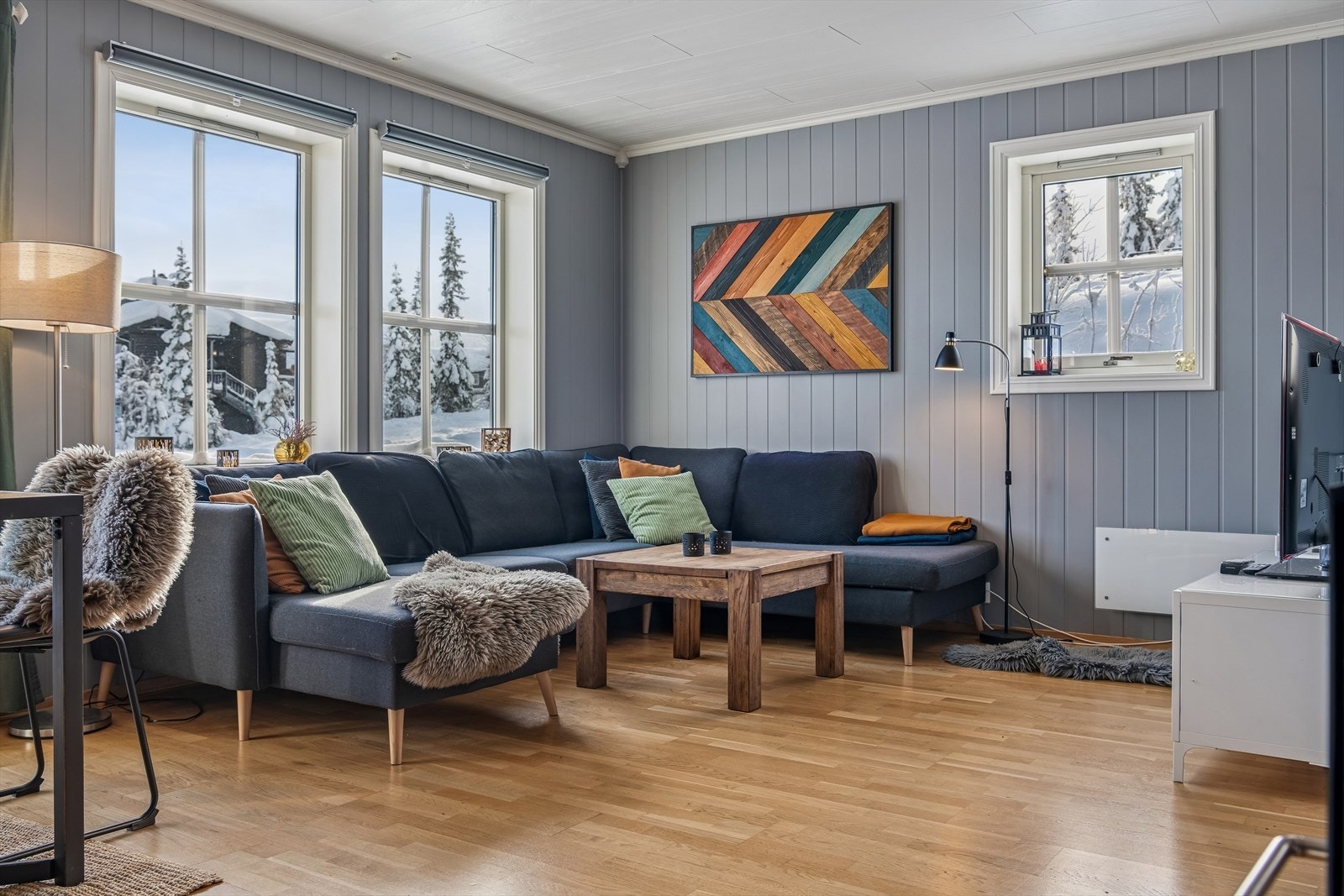 Stuen er et sosialt samlingspunkt med parkett på gulv og vegger med MDF-plater. Galleribilde