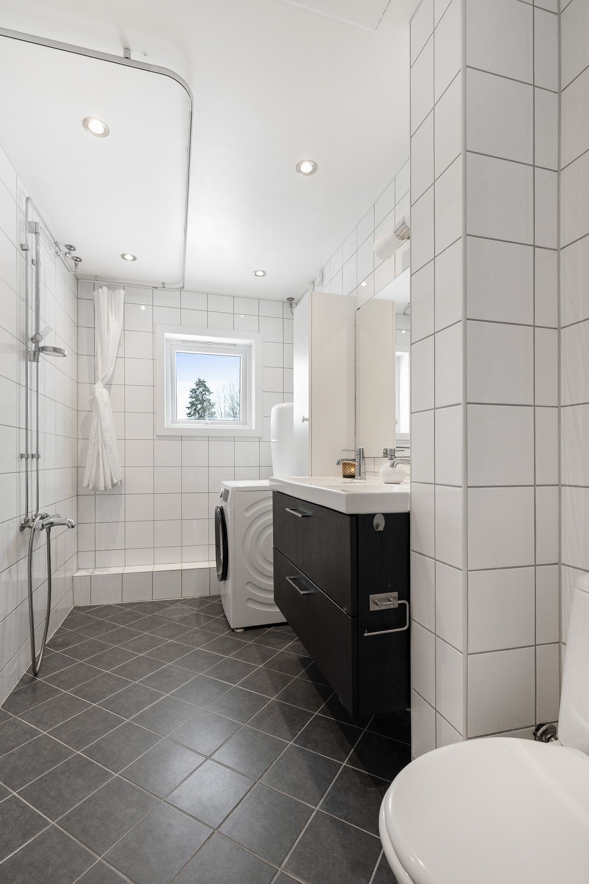 Badet er utstyrt med toalett, dusjnisje, servant og opplegg for vaskemaskin, noe som gjør rommet både funksjonelt og praktisk i hverdagen. Galleribilde