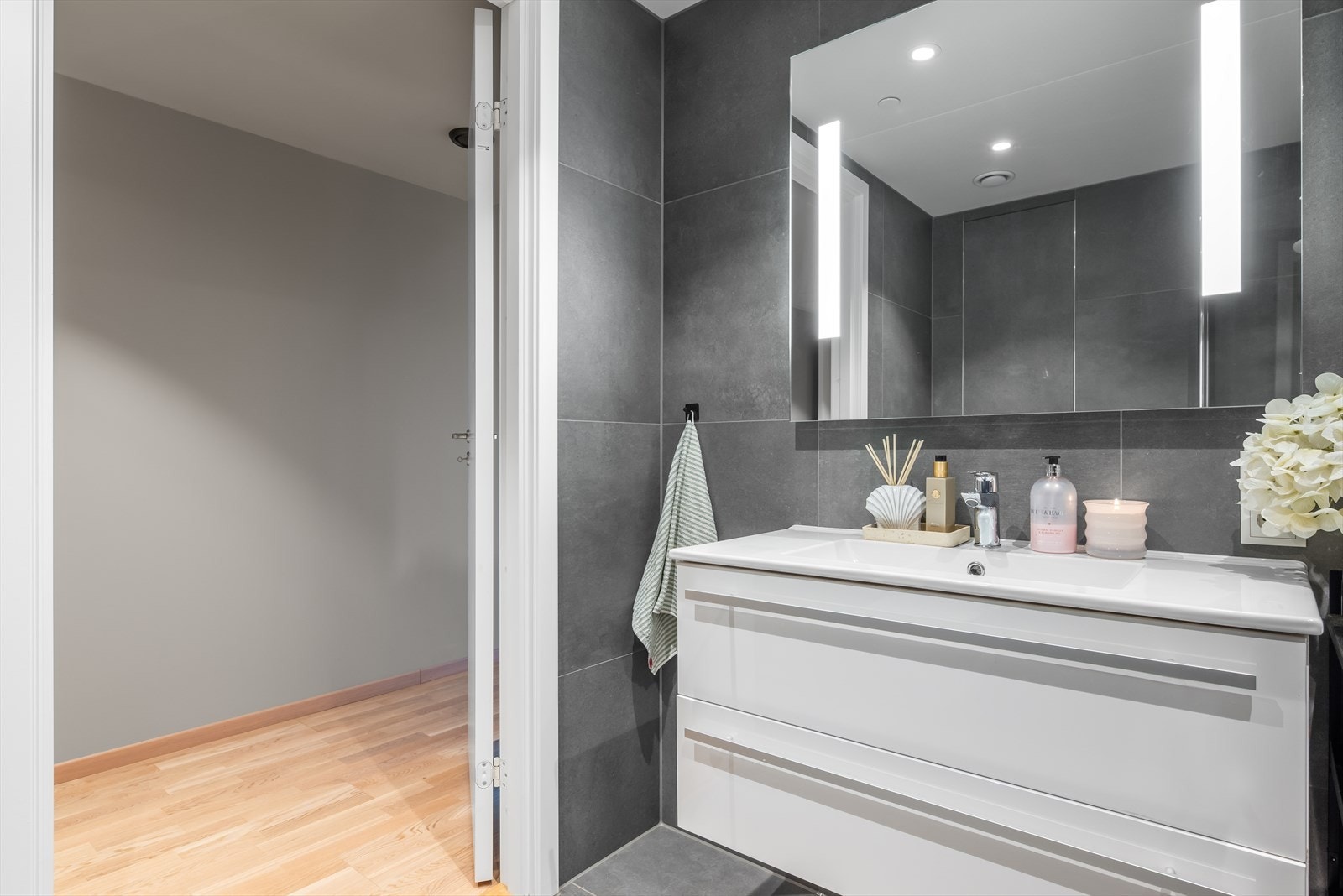 Videre får du en pen, tidløs innredning med heldekkende servant, speil med integrert belysning og opplegg for vaskemaskin. Galleribilde