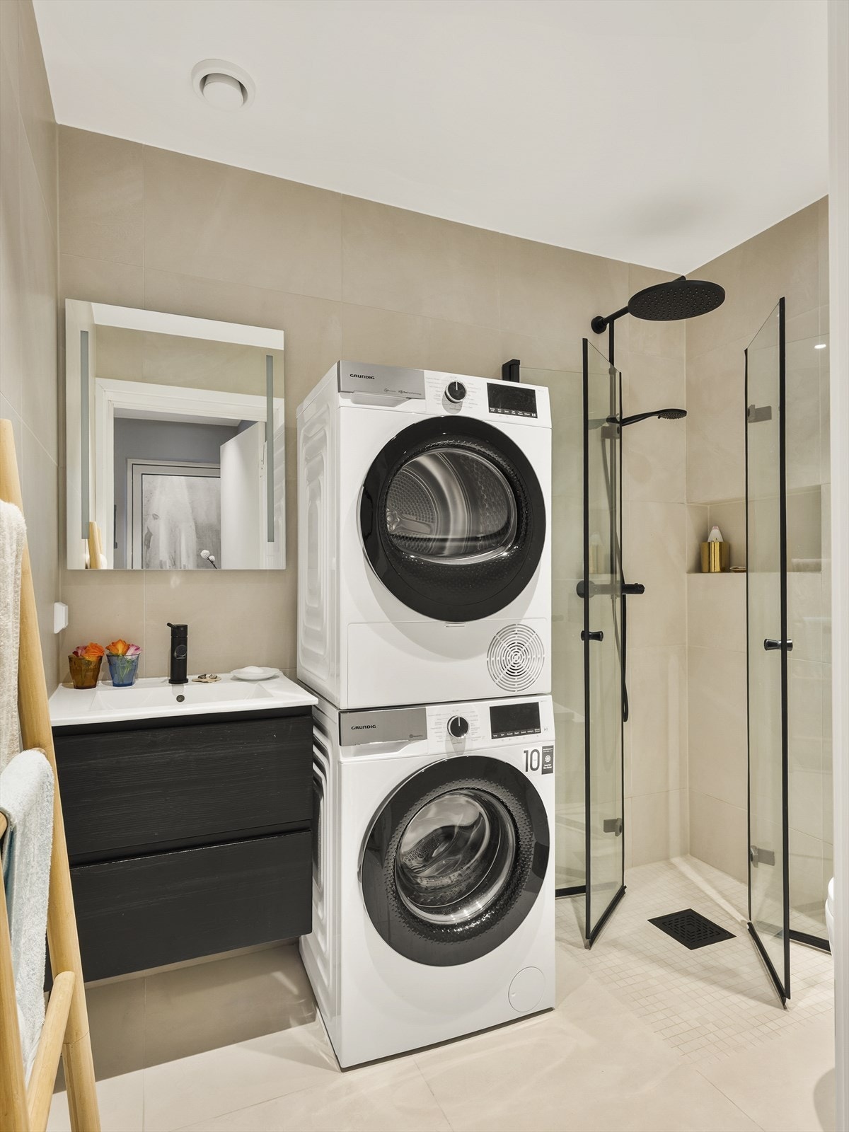 Delikat, flislagt bad med vegghengt toalett, dusjhjørne og opplegg for vaske-tørkesøyle. Galleribilde