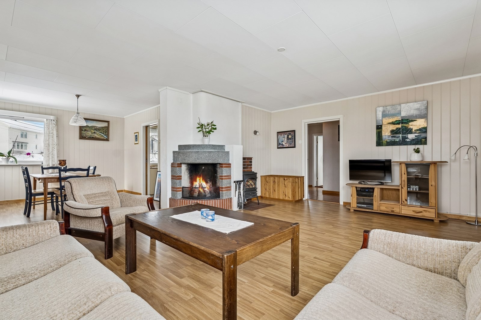 En teglsteinspipe med peisovn samt åpen peis gir varme og atmosfære i stuen. Galleribilde