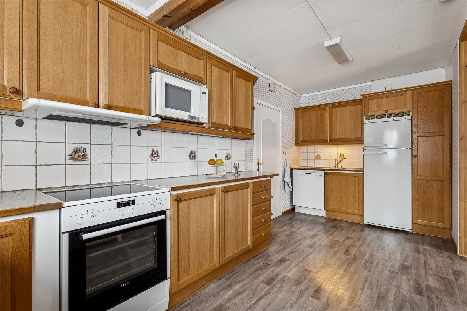 Innholdsrik innredning med plass for frittstående komfyr, kjøleskap og oppvaskmaskin. Galleribilde