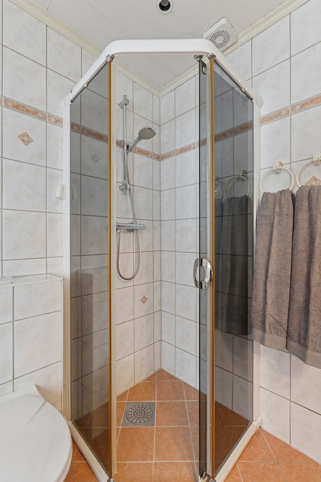 Badet er innredet med veggmontert toalett, badekar og dusjhjørne, samt en nedfelt servant med underskap. Speil og overskap over servanten. Galleribilde