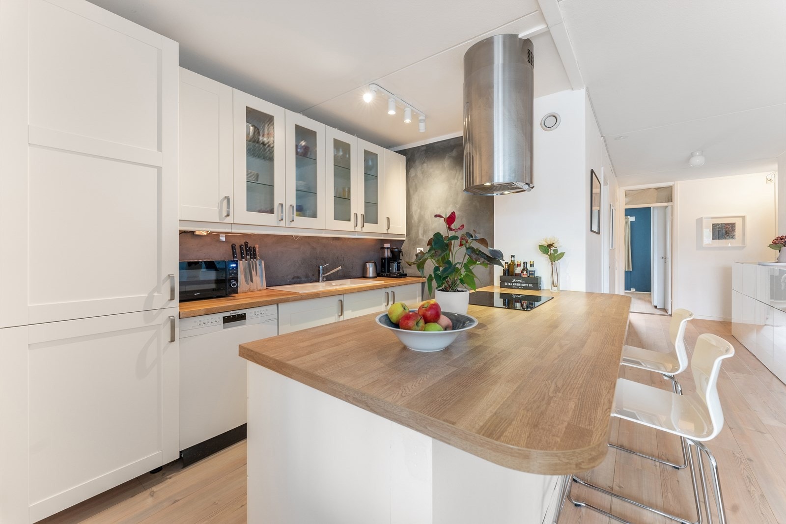 Moderne kjøkkeninnredning med integrerte hvitevarer, stor øy og rikelig med benkeplass. Galleribilde