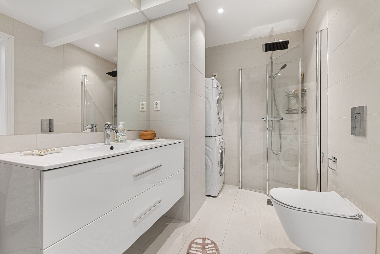 Badet er utstyrt med toalett, dusjsone med hånd- og regndusj, frittstående badekar og opplegg for vaskemaskin og tørketrommel. Galleribilde