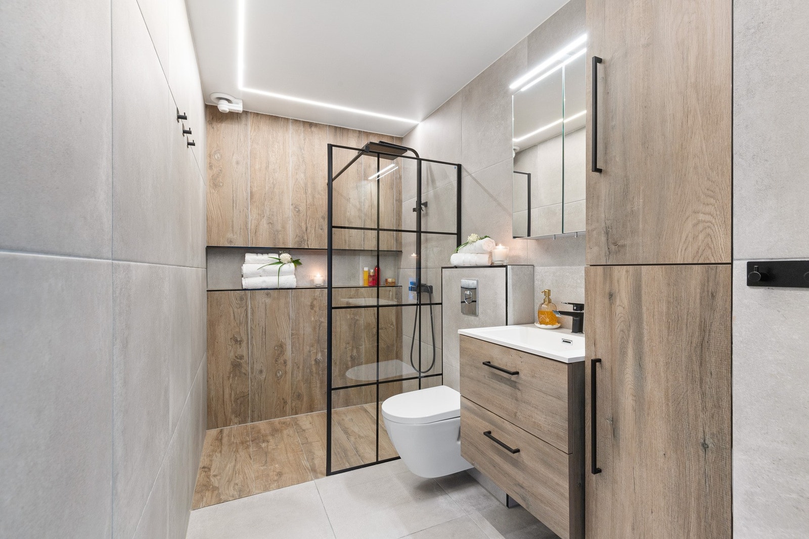 Rommet har innredning med nedfelt servant, speil med lys, veggmontert toalett og dusjhjørne. Galleribilde