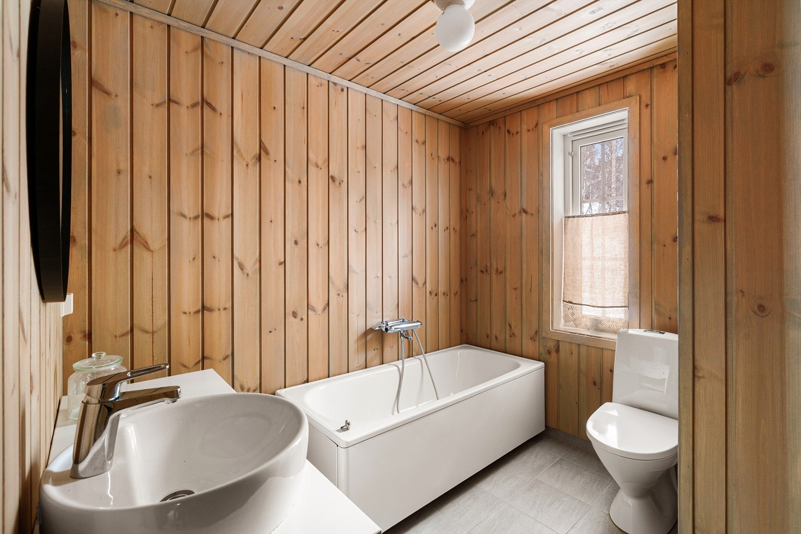 Ett av to bad. Her med badekar. Varme i gulv og lune toner på vegg. Galleribilde