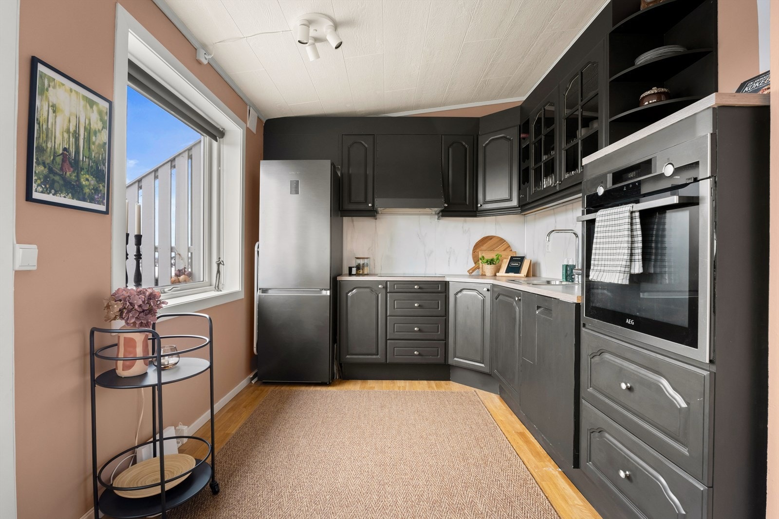 Sort kjøkken med lekre detaljer på fronter, laminert benkeplate og oppvaskkum. Galleribilde