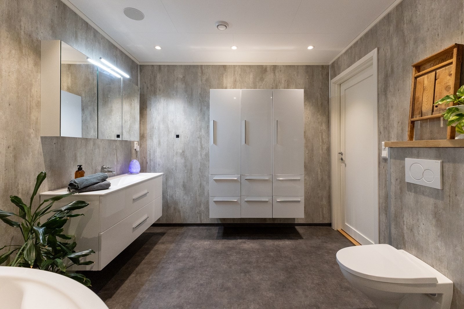 Innfelte høytalere og downlights i himling. Ekstra stor innredning på badet og speilskap med LED belysning, samt store skuffer under vask. Veggmontert wc med trykkbetjening. Galleribilde