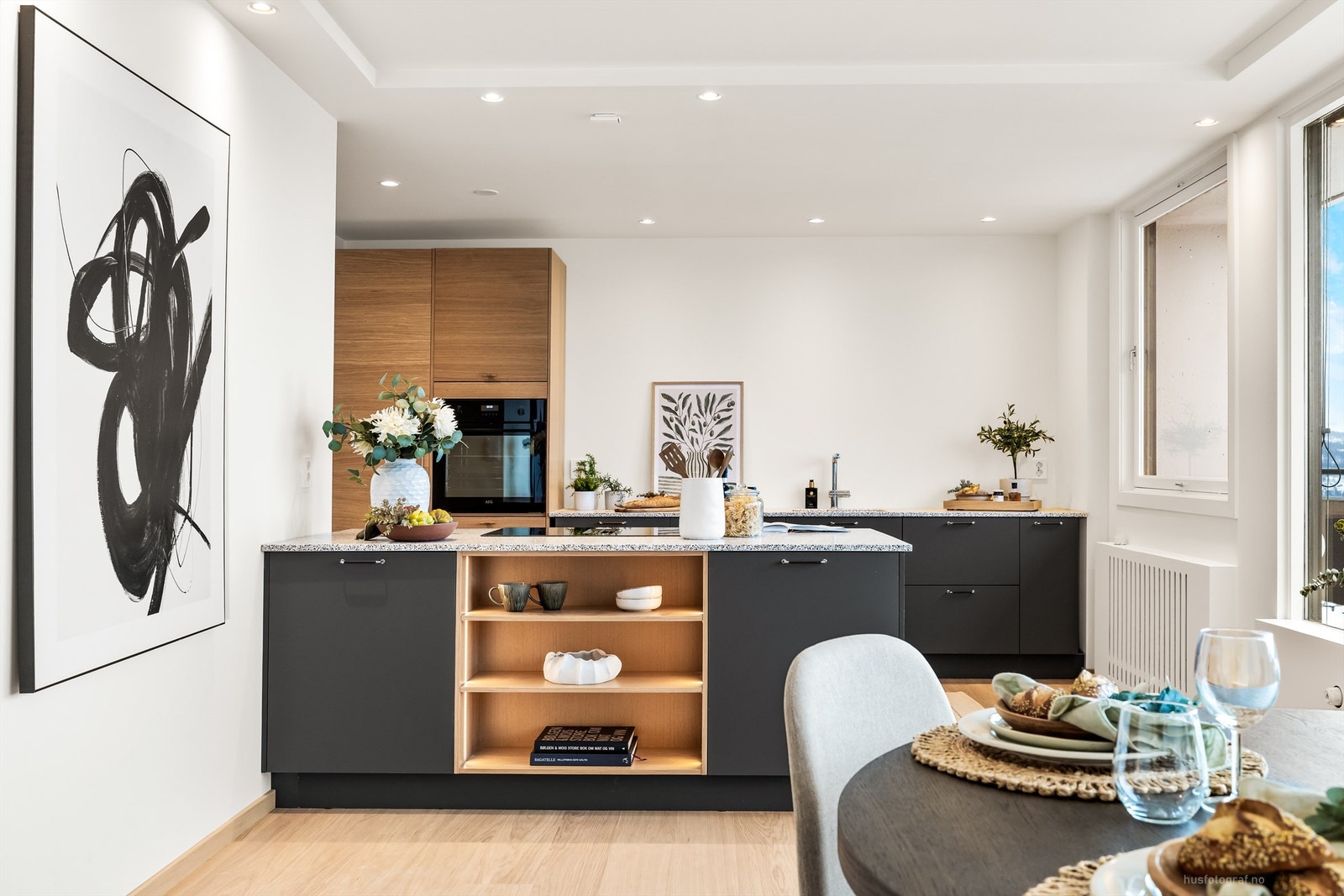 Kjøkkenhalvøya fungerer som en naturlig romdeler med praktisk oppbevaring og ekstra arbeidsflate. Galleribilde