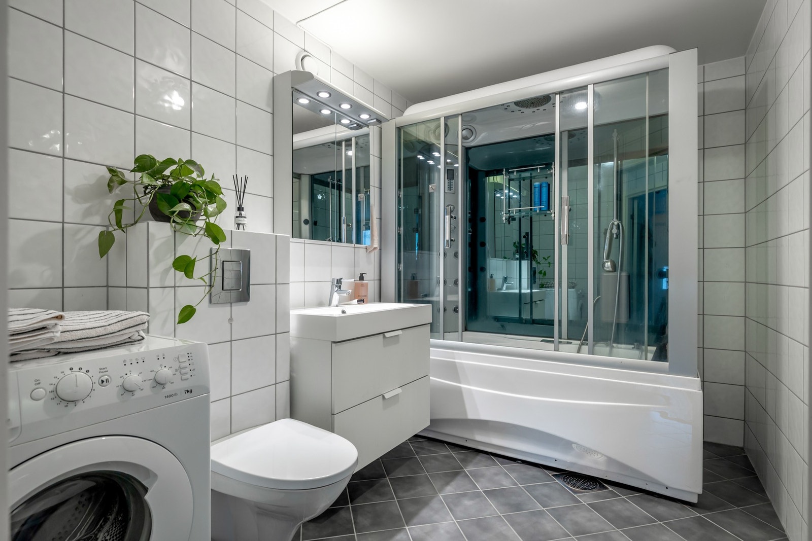 Badet er romslig og har flislagte gulv og vegger, samt malt himling. Overflatene fremstår som funksjonelle og godt vedlikeholdt. Galleribilde