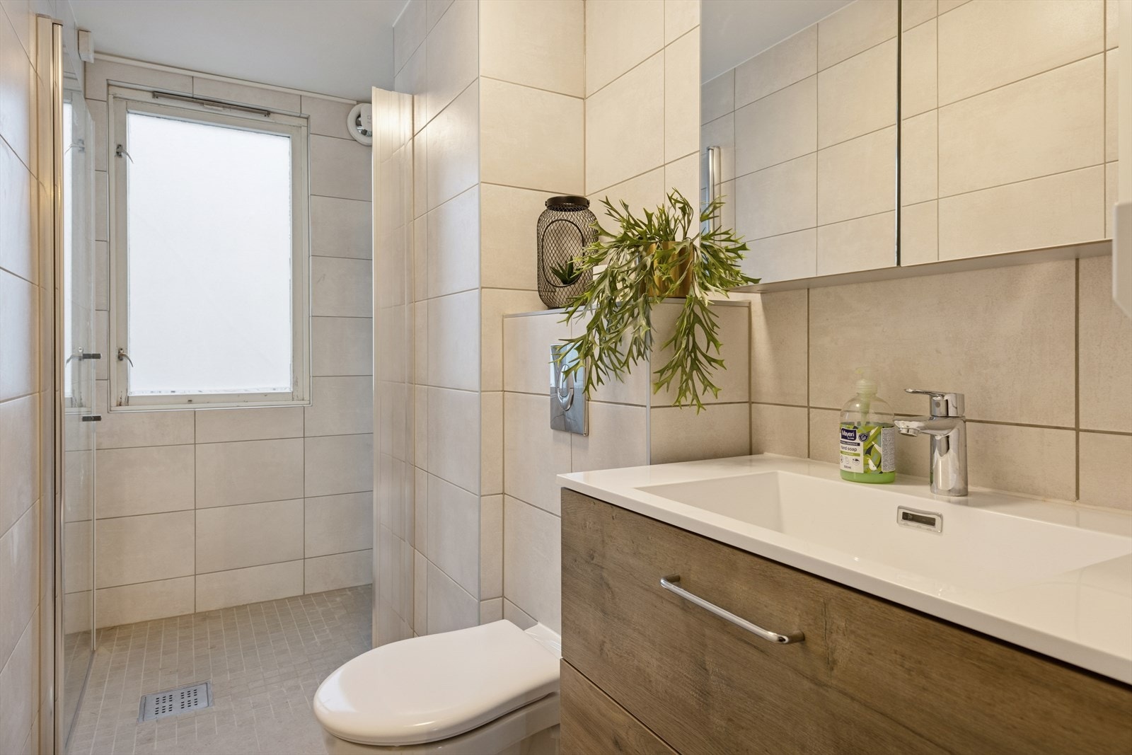 Flislagte overflater på gulv og vegger gir et robust inntrykk på badet. Det er etablert mekanisk avtrekk med fuktsensor for effektiv ventilasjon. Galleribilde