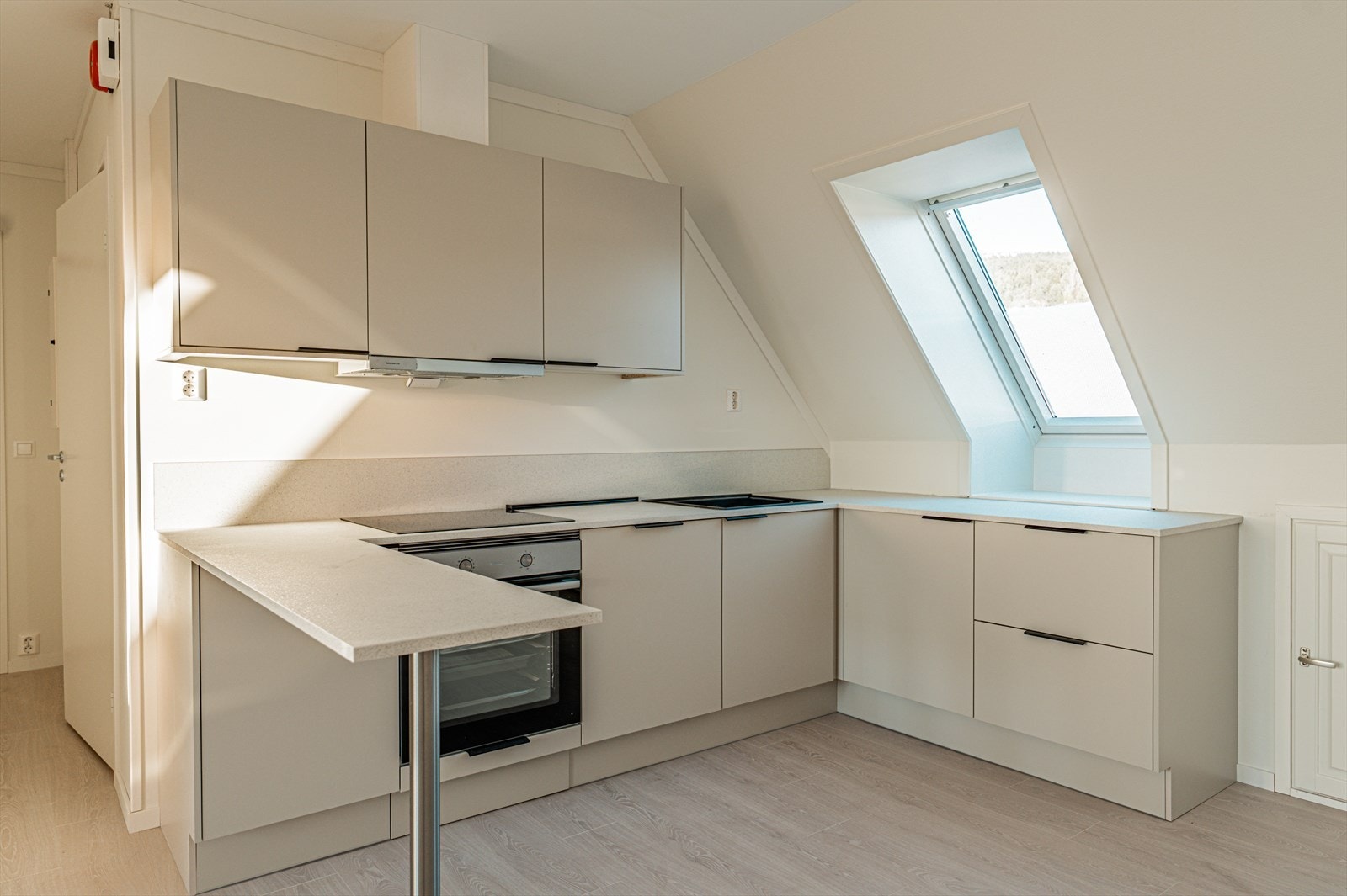 Over benkeplaten er det laminatplate på veggen. Kjøkkenvifte med avtrekk ut over taket. God skap- og benkeplass. Galleribilde