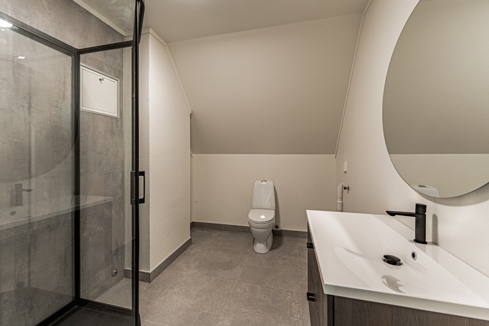 Innbydende bad (pusset opp i 2025/2026). Fliser og varme i gulv. Baderomsplater på veggene. Rommet er innredet med baderomsinnredning med heldekkende servant, vegghengt toalett, dusjkabinett og opplegg for vaskemaskin. Galleribilde