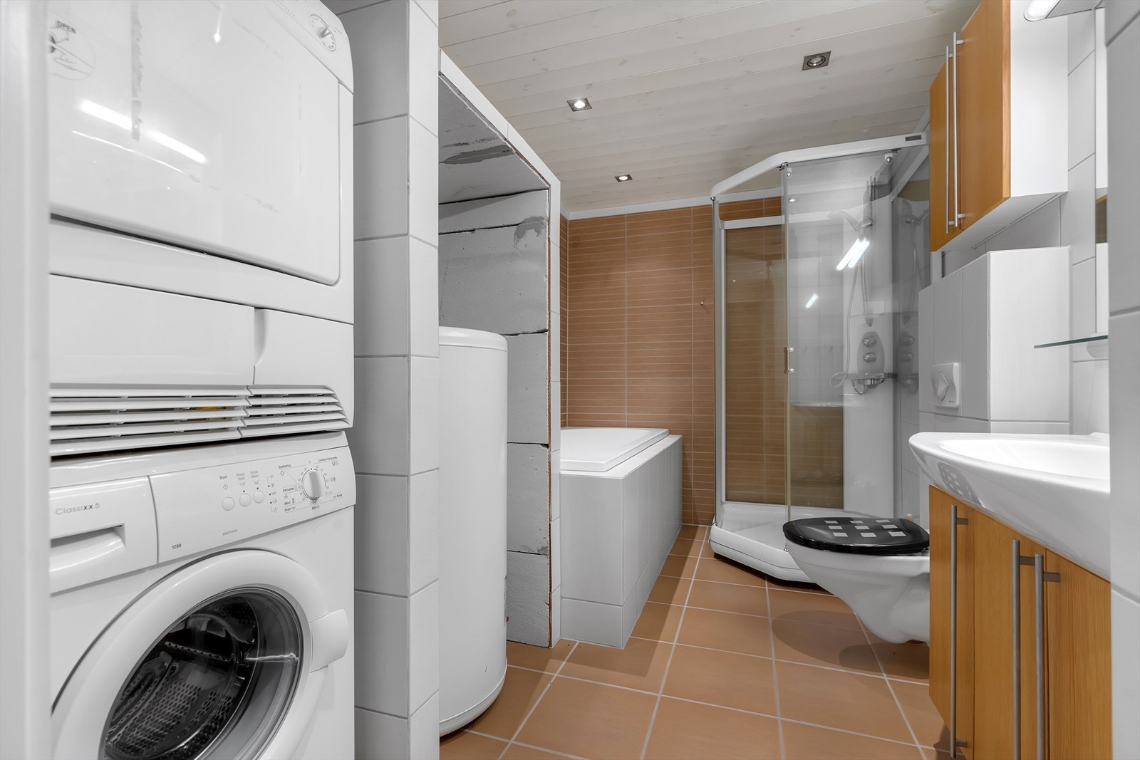 Badet har badekar, dusjkabinett, veggehengt toalett og servant med underskap. Opplegg til vaskemaskin og tøretrommel. Galleribilde