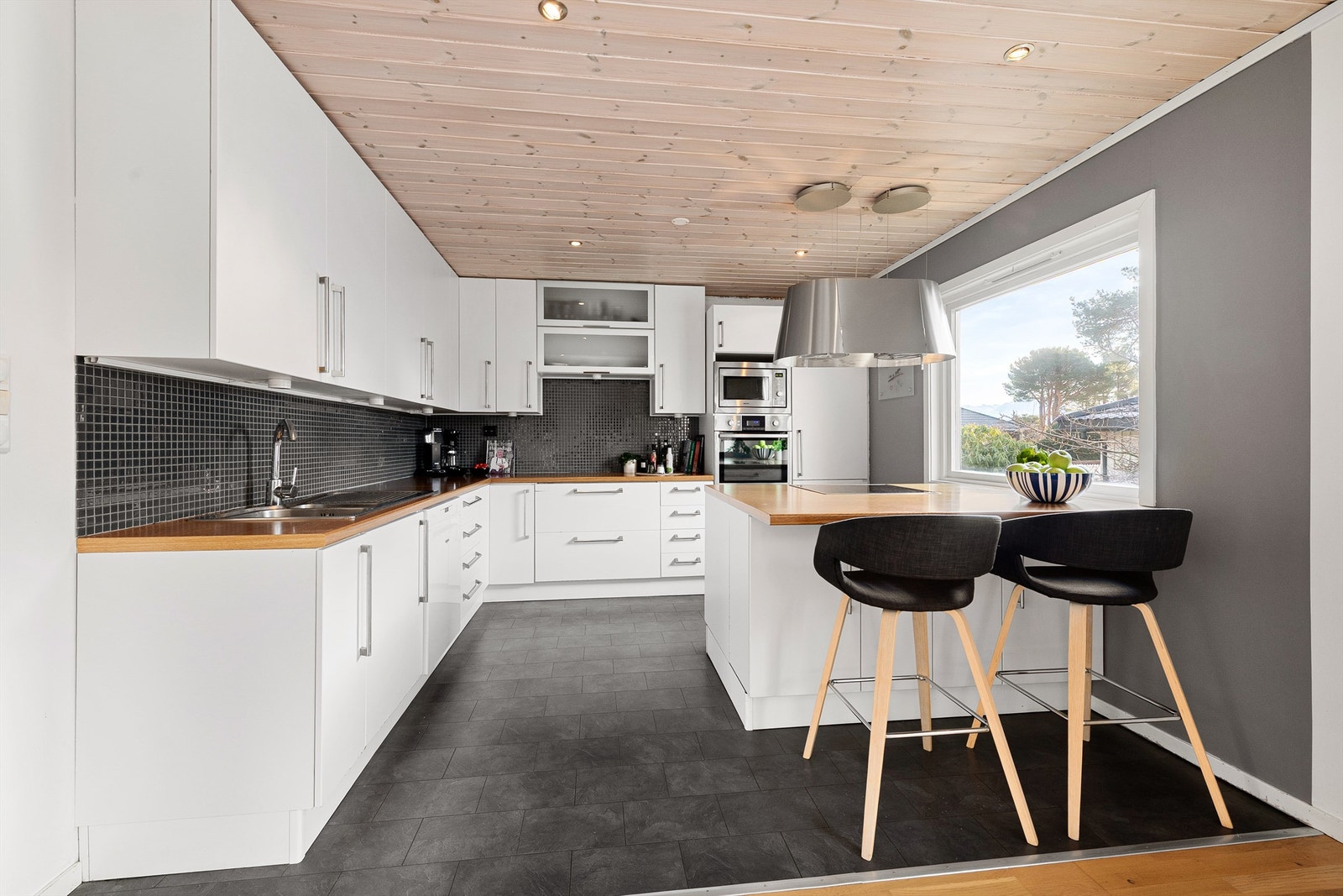 Kjøkkeninnreding med glatte fronter fra ca. 2006. Benkeplate av laminat. Flislagt mellom kjøkkenbenk og overskap. Galleribilde