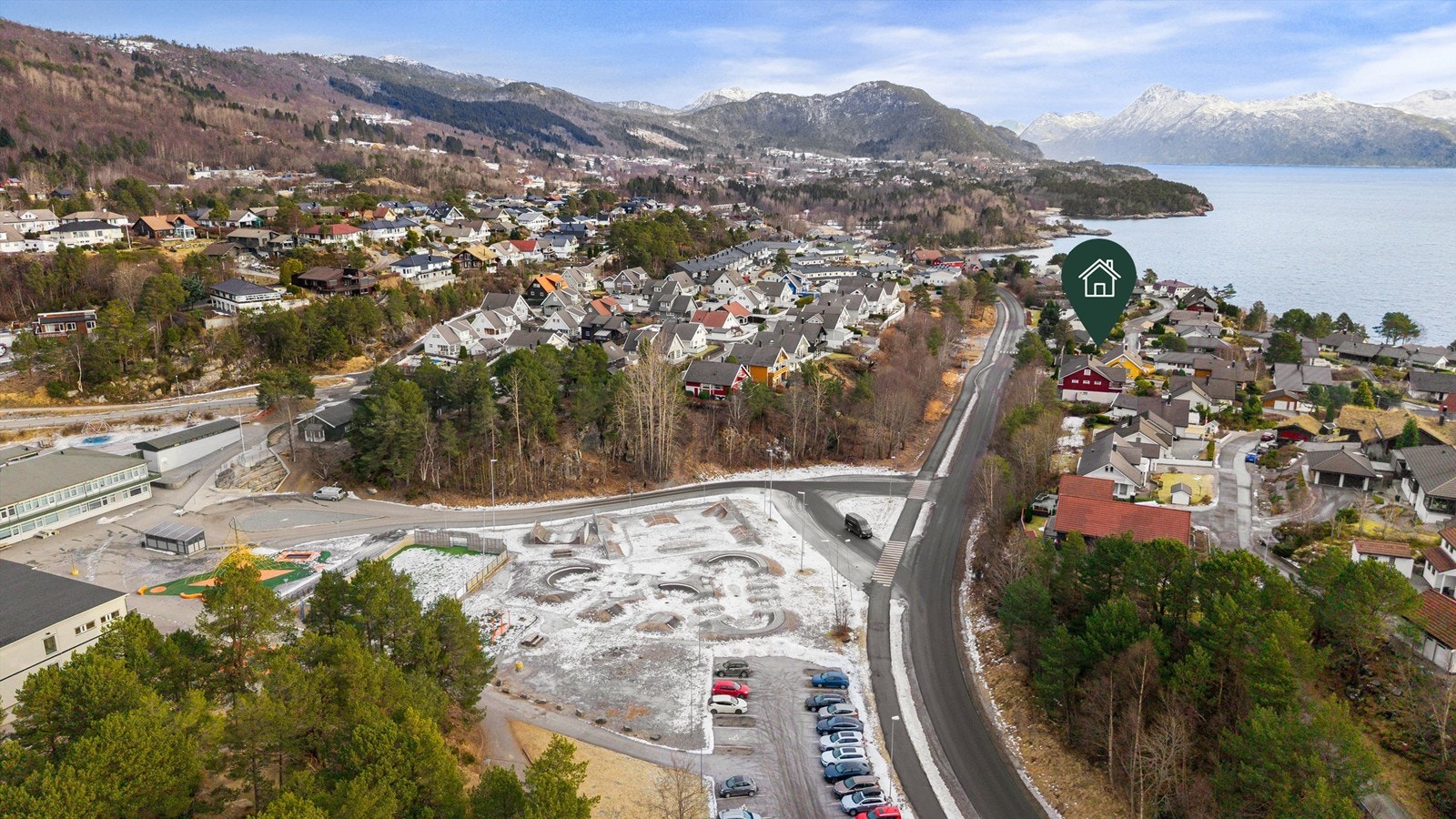 Dronebilde av nærområdet med Flisnes Barneskole i fremkant samt eiendommens plassering Galleribilde