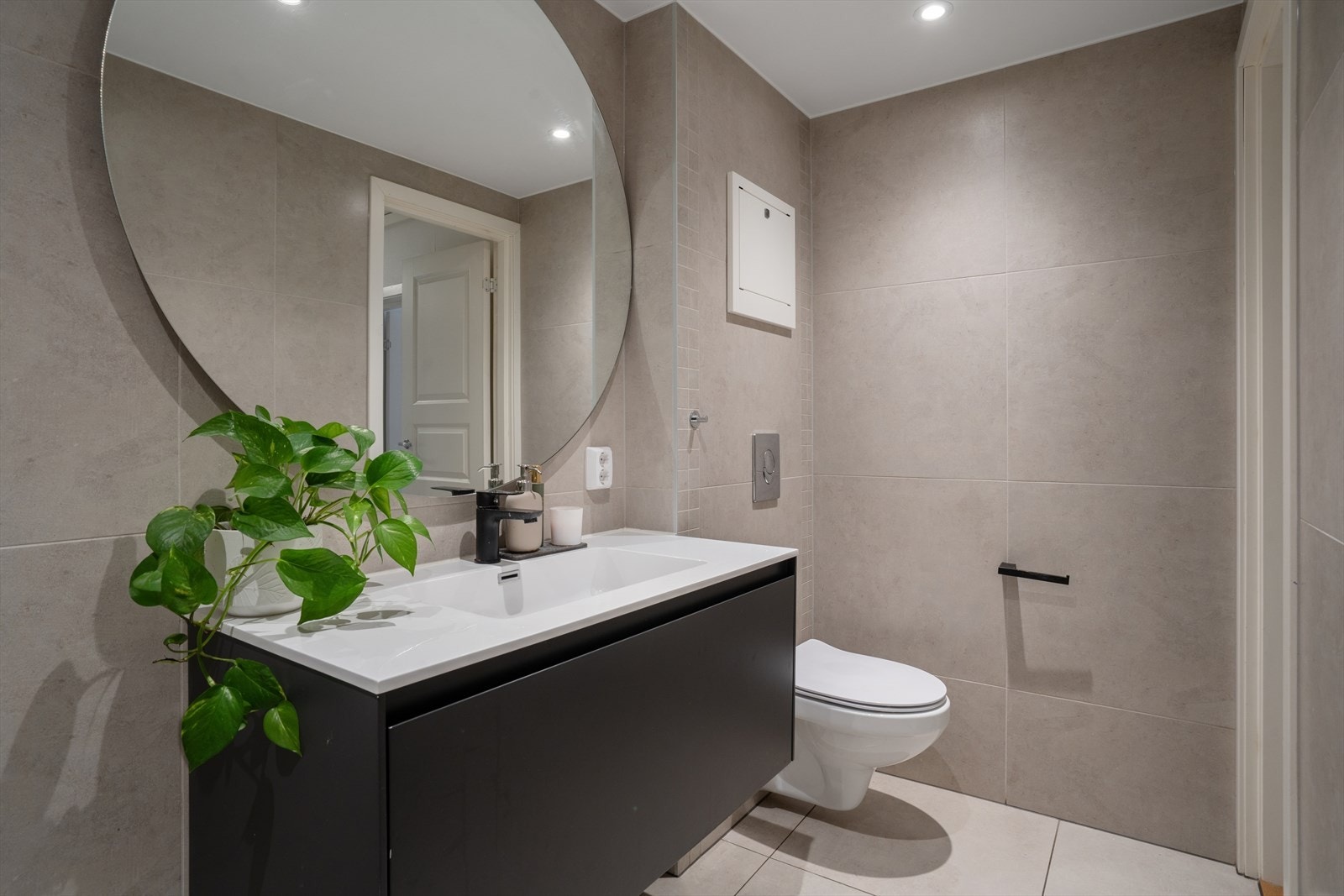 Moderne innredning med servant, skuffer og et rundt speil med elegant bakbelysning. Galleribilde