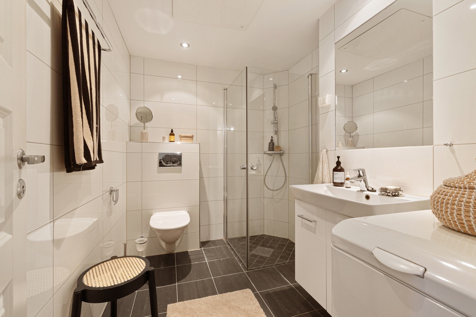 Flilagt bad med toalett, dusjhjørne med glassdører, samt et servantskap med hvit keramikkservant og ettgreps blandebatteri fra Hans Grohe. Galleribilde