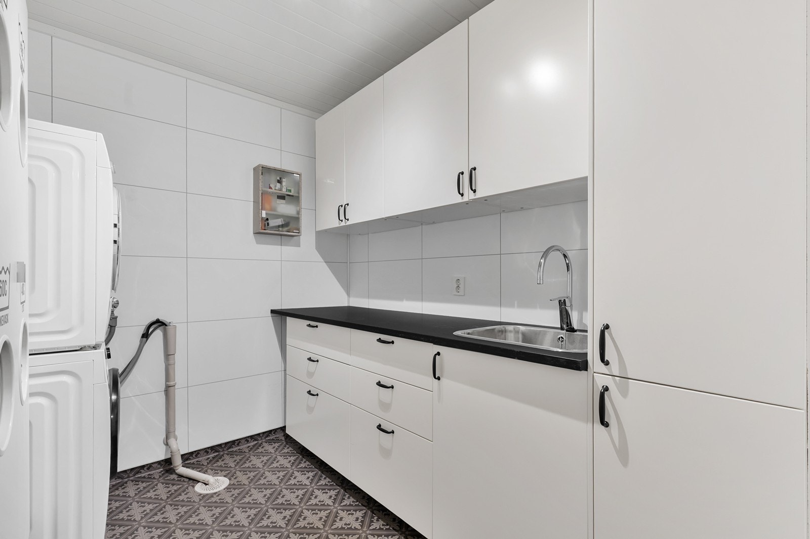 Rommet er innredet med benkeplate, skyllekum og overskap, samt opplegg for vaskemaskin. Galleribilde