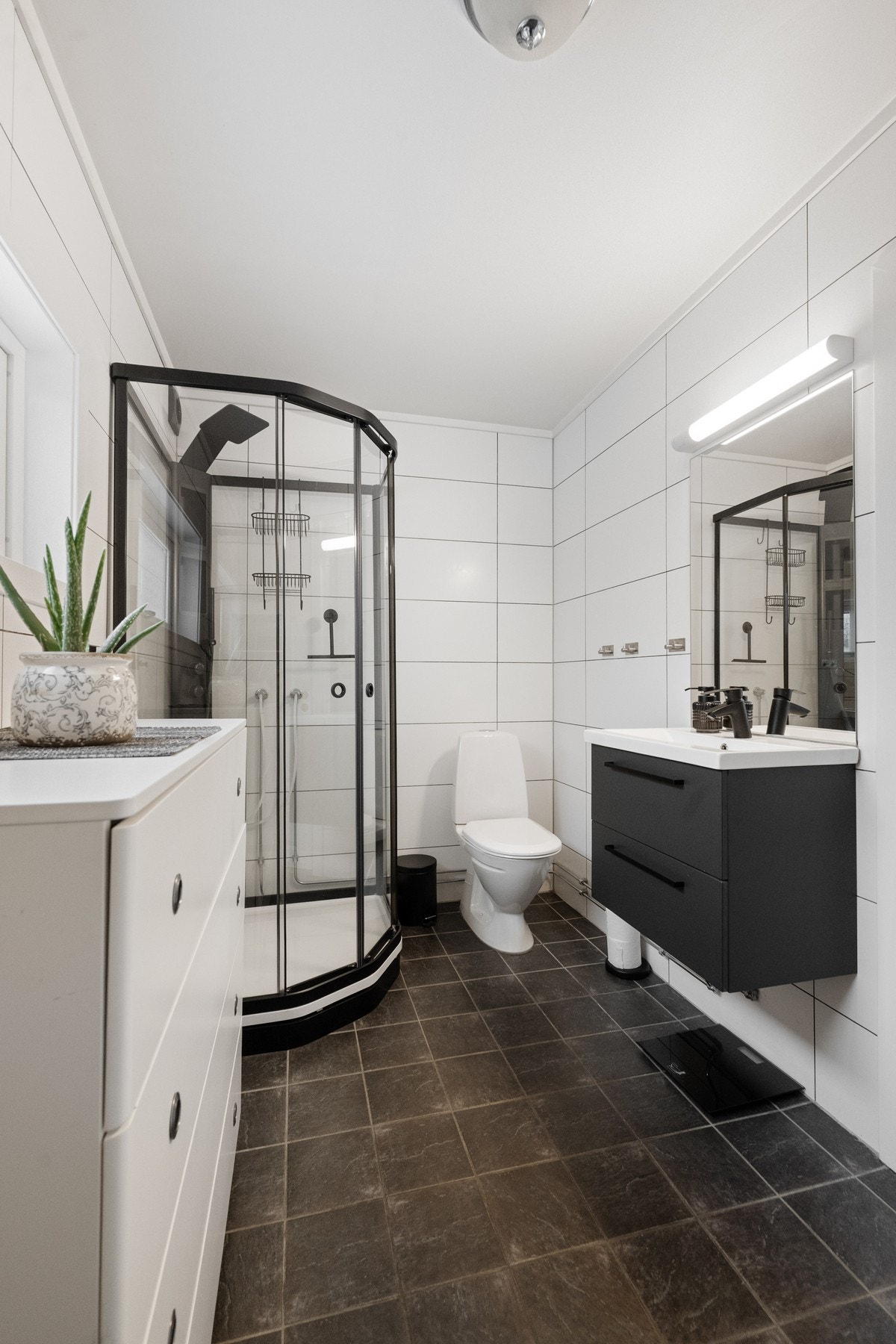 Praktisk bad/vaskerom med fliser på gulv og vegger samt malte plater i himling. Galleribilde