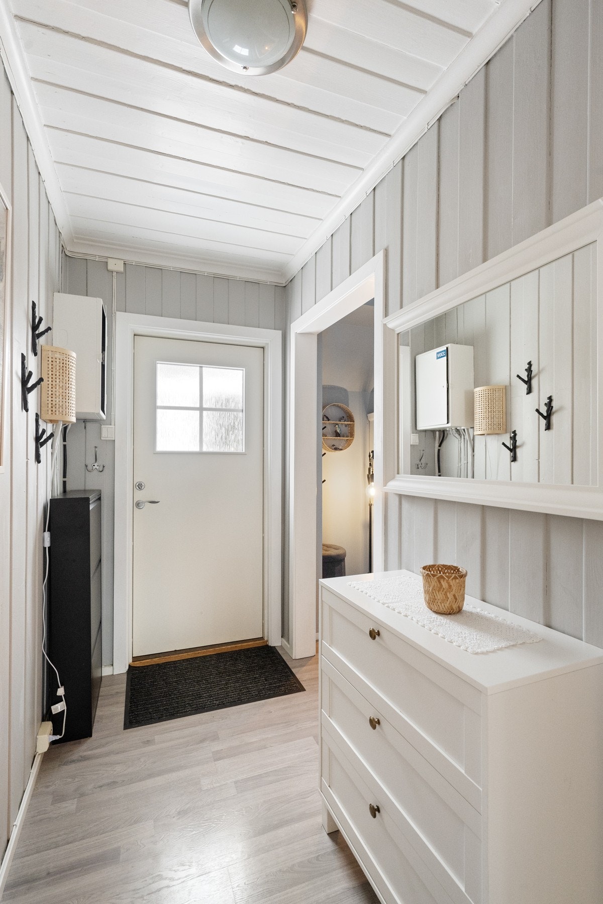 Lys og innbydende entré med malt trepanel på vegg som gir et lunt førsteinntrykk. Galleribilde