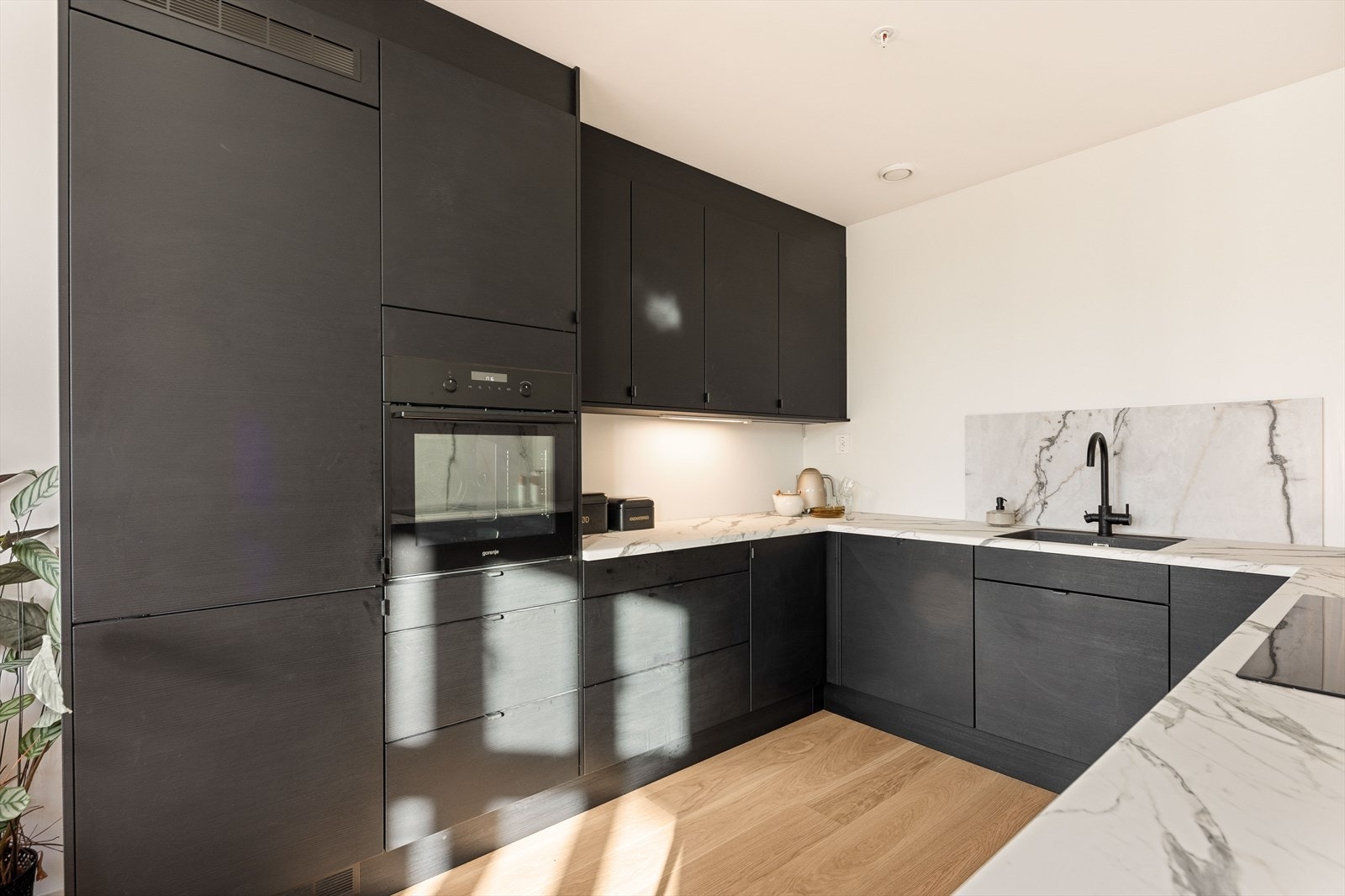 Kjøkkeninnredningen er godt tilpasset rommets utforming og har rikelig med skap- og benkeplass Galleribilde