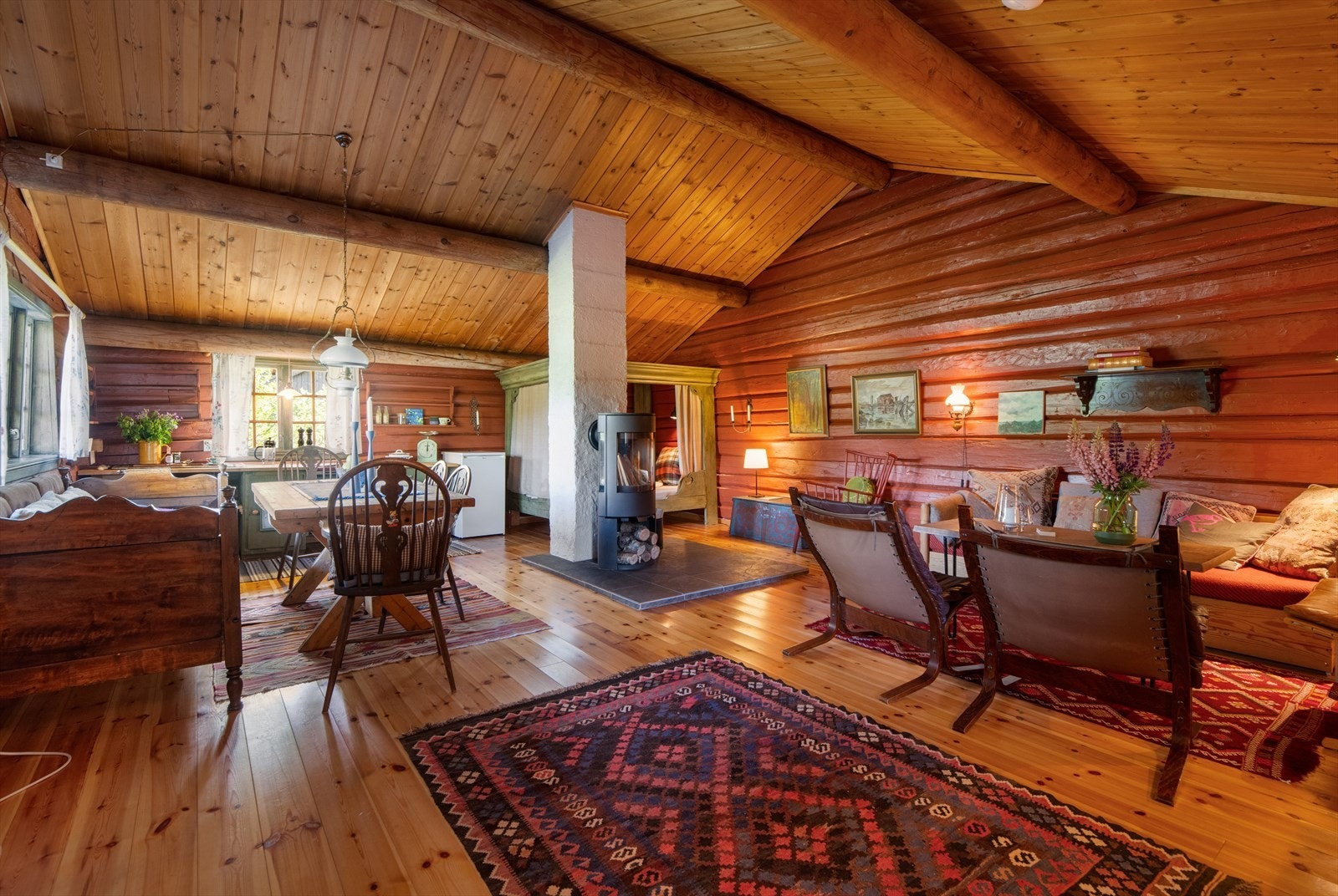 Stuen og kjøkkenet ligger i åpen løsning i et stort og flott allrom med god takhøyde, fantastiske tømmervegger og furugulv. Galleribilde