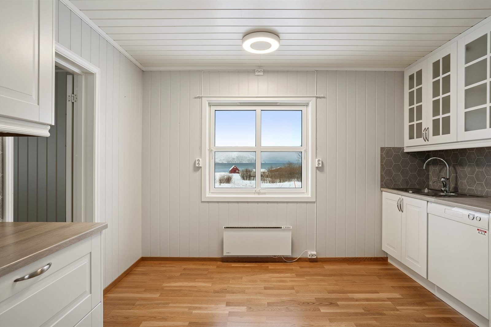 Det er montert belysning under overskapene, og veggen over benken er kledd med våtromsbelegg. Galleribilde