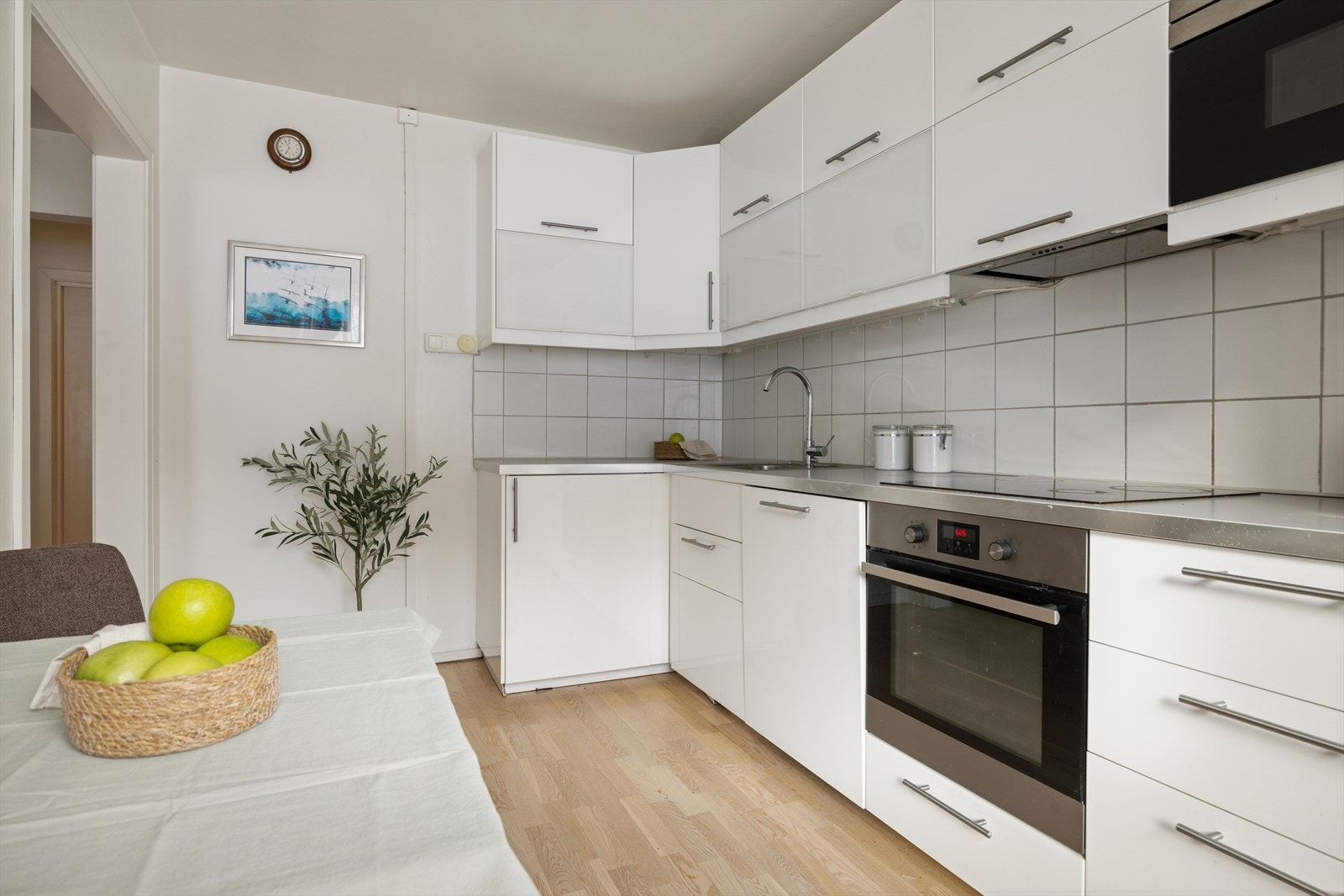 Kjøkkeninnredning med glatte, hvite fronter og benkeplate i stål. Galleribilde