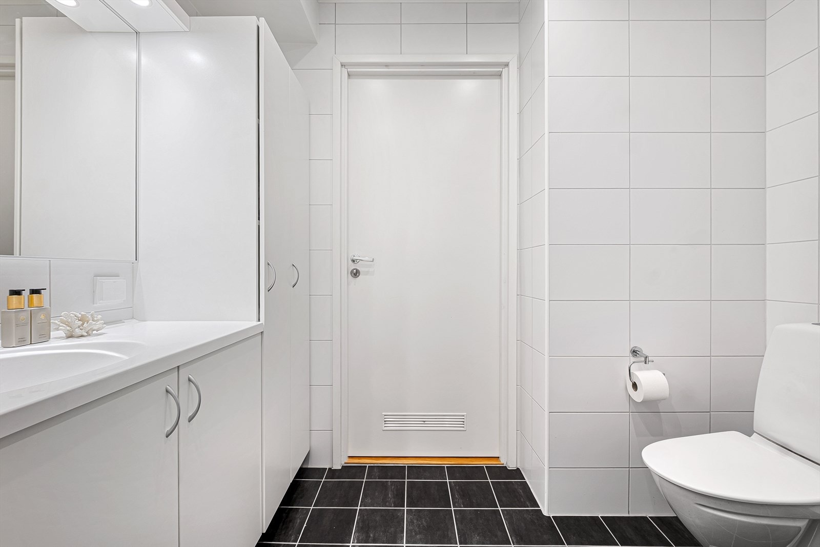 Badet er stilrent med mørke gulvfliser m/varmekabler under og hvite veggfliser Galleribilde