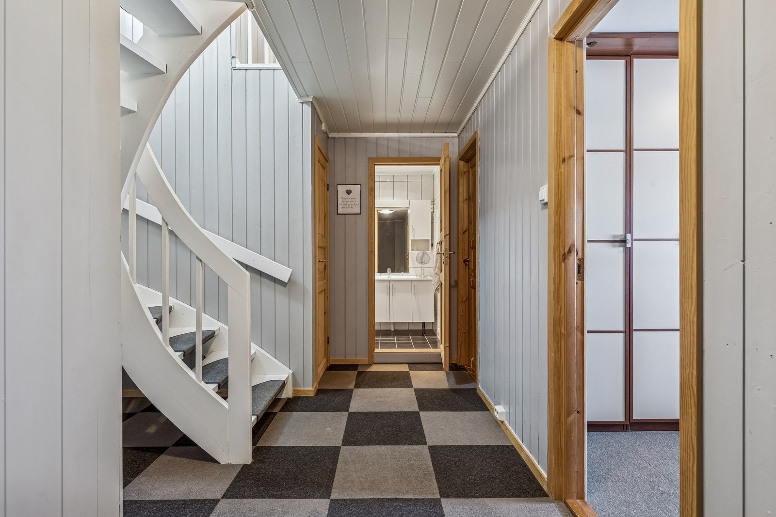 Den malte svingtrappen med teppefliser i trinnene leder ned til soveavdelingen. Galleribilde