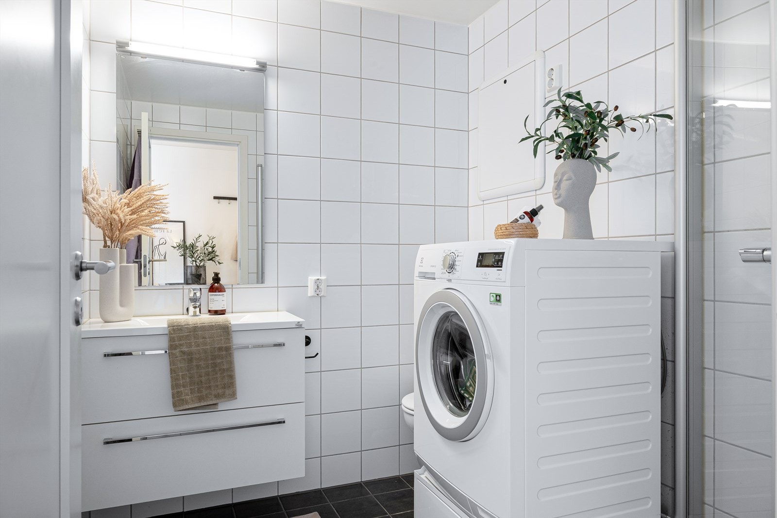 Det inneholder vegghengt toalett, servant med underskap, dusj med innfellbare glassdører og opplegg var vaskemaskin. Galleribilde