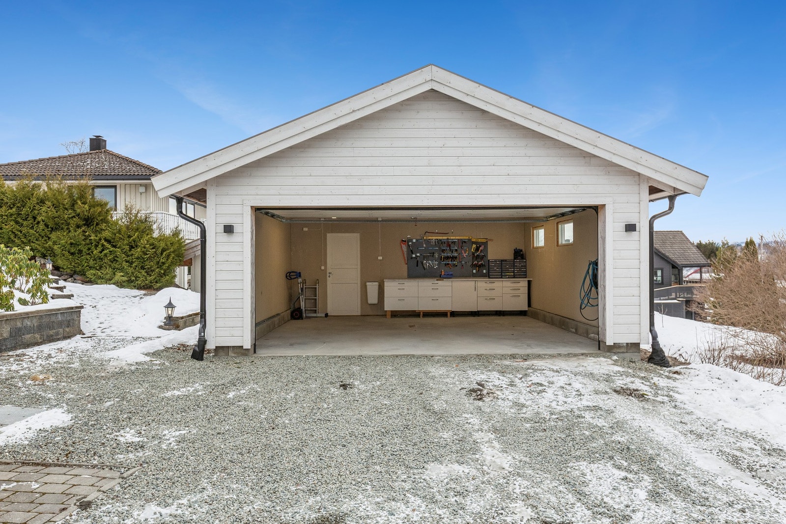 Flott isolert dobbelgarasje med en romslig bod i bakkant. Montert innredning med en praktisk benkeplate Galleribilde
