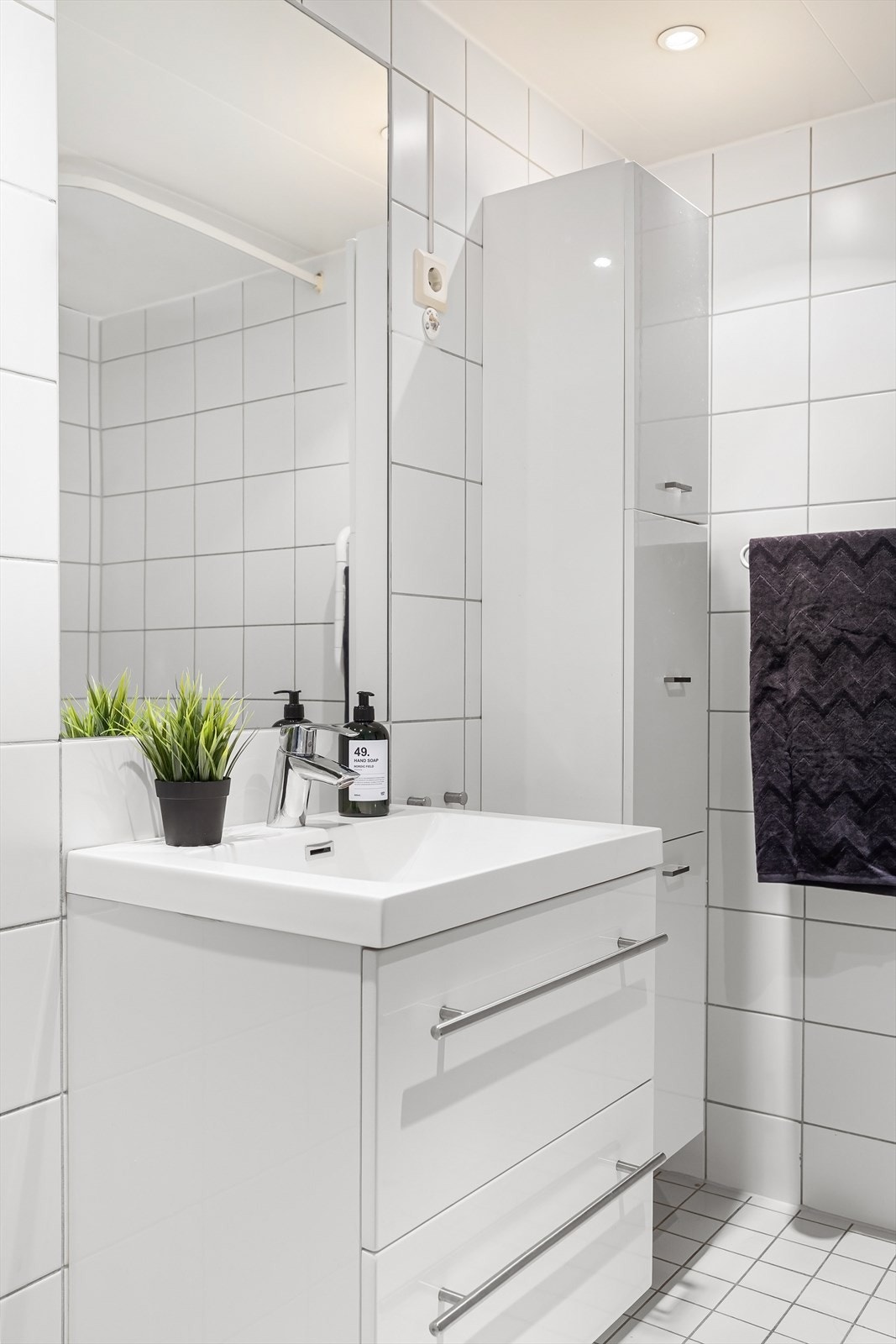 Badet er utstyrt med vegghengt toalett, dusjhjørne, heldekkende servant med skuffeinnredning, samt opplegg for både vaskemaskin og tørketrommel. Galleribilde