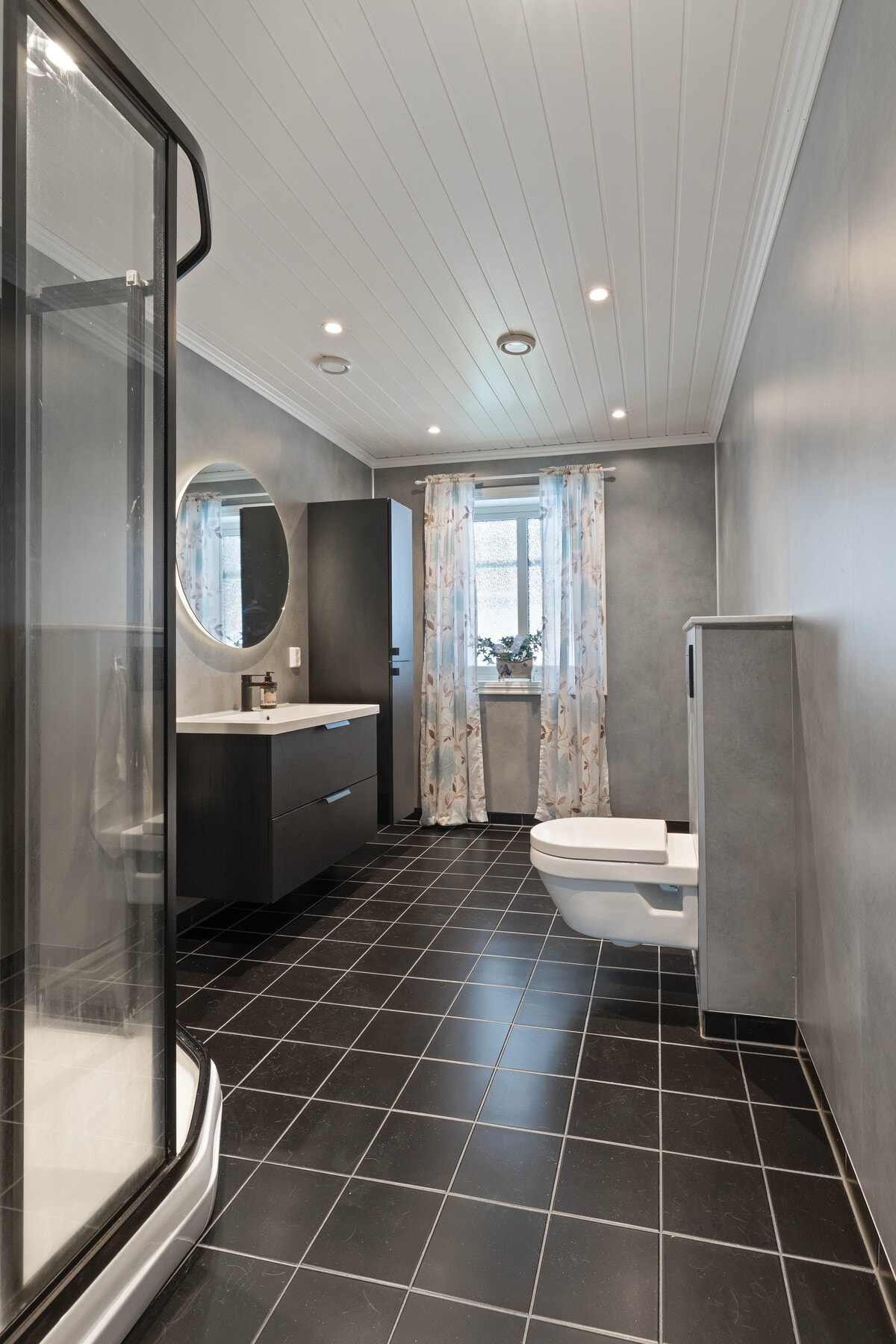 Det er flislagt gulv med elektriske varmekabler og plastsluk. Veggene har våtromsplater og det er mekanisk ventilasjon med ventil i tak. Galleribilde